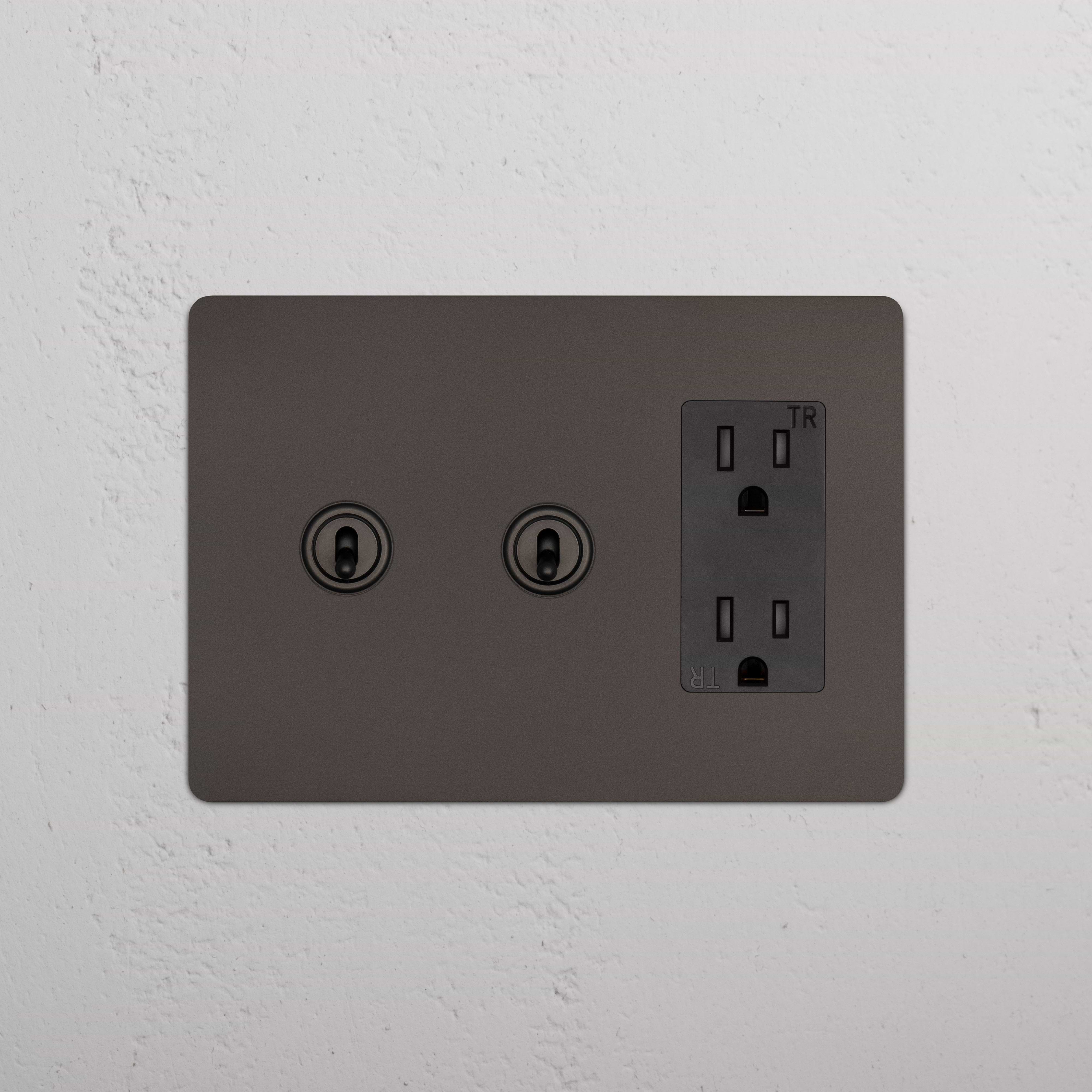 Kew 3G 2x Toggle Switch & Outlet in Bronze Black with two toggles and one three-prong outlet on a wall.