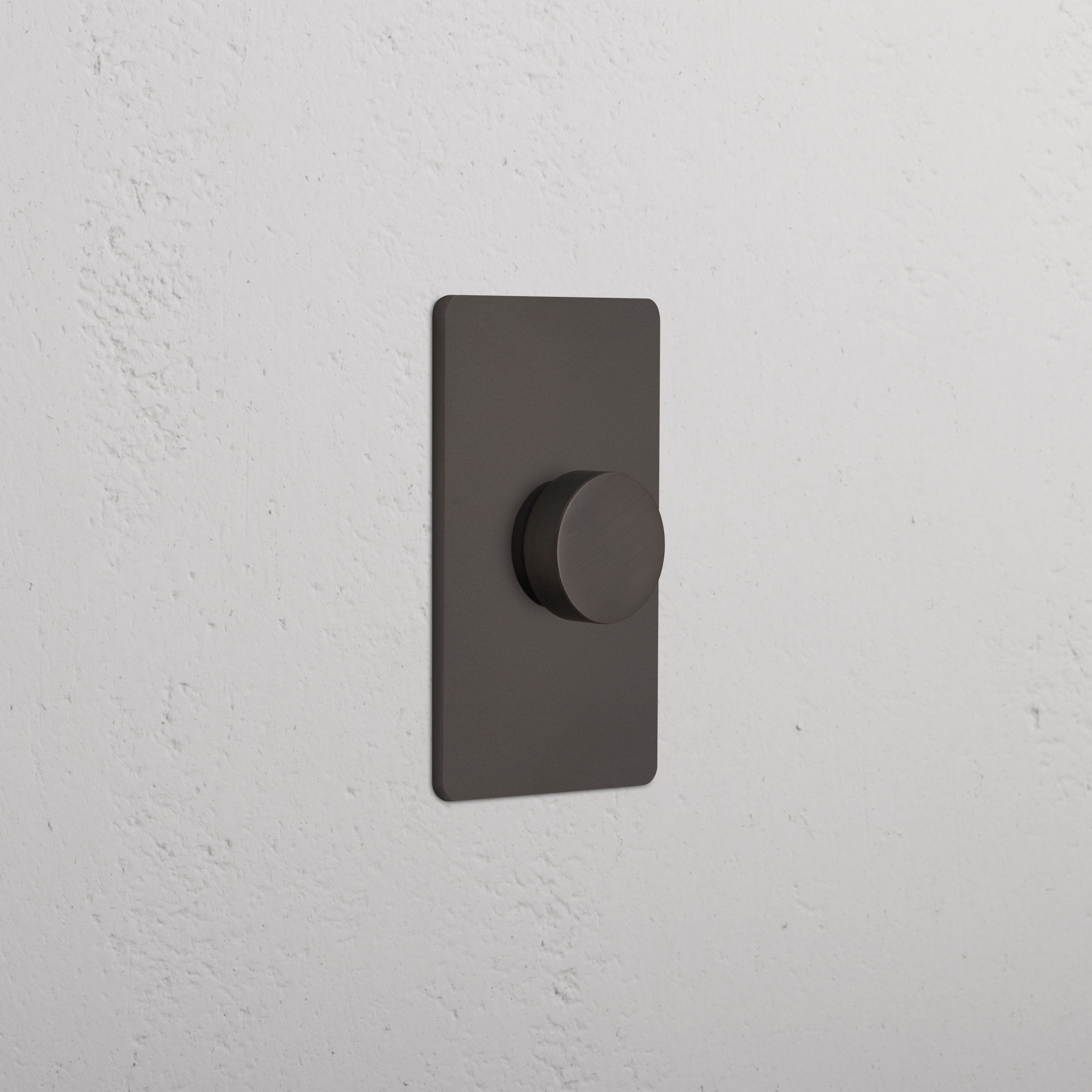 Grove 1G Dimmer Switch in bronze finish with round knob, mounted on a white textured wall.