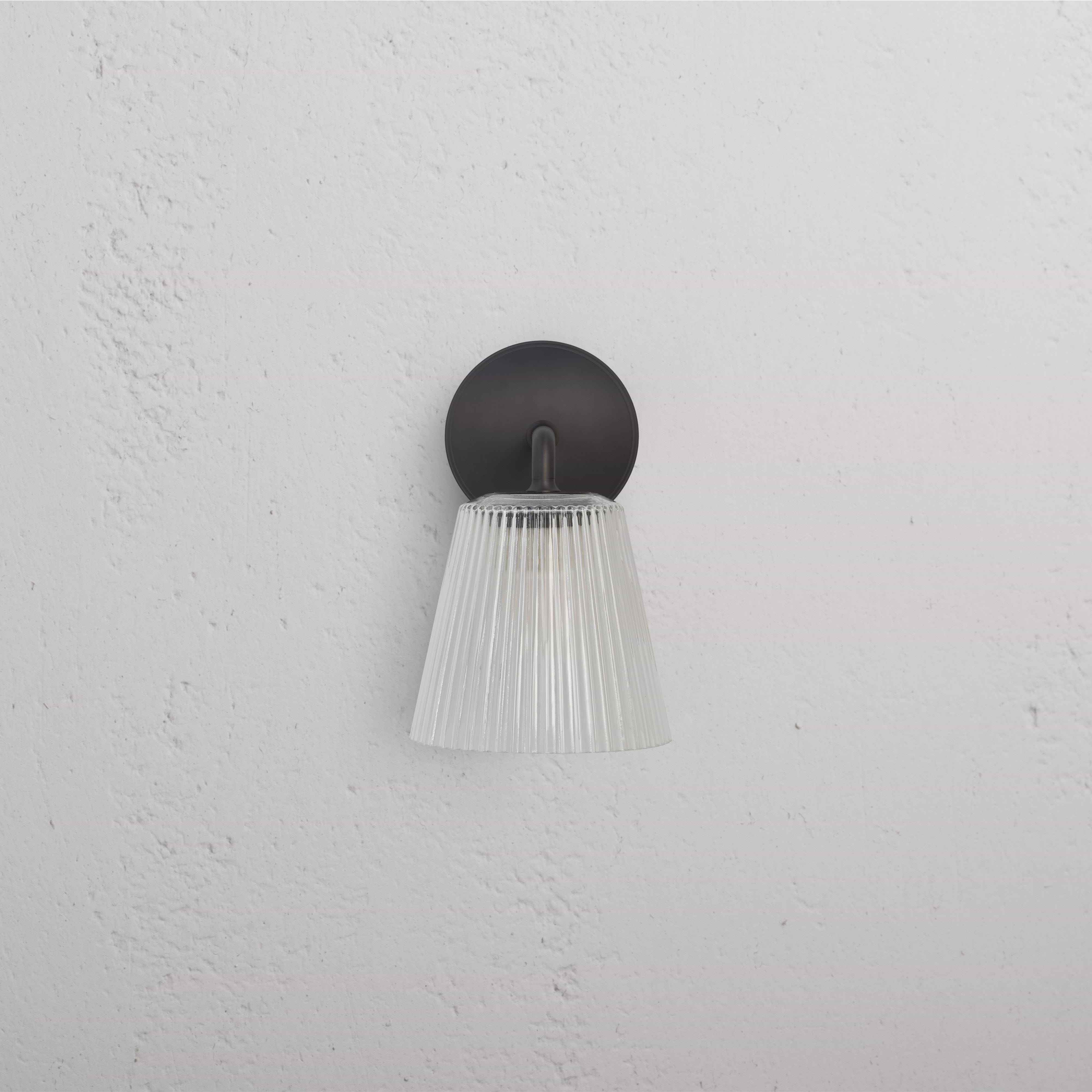 Richmond Medium Wall Light with fluted clear glass shade and bronze base, mounted on a white wall.