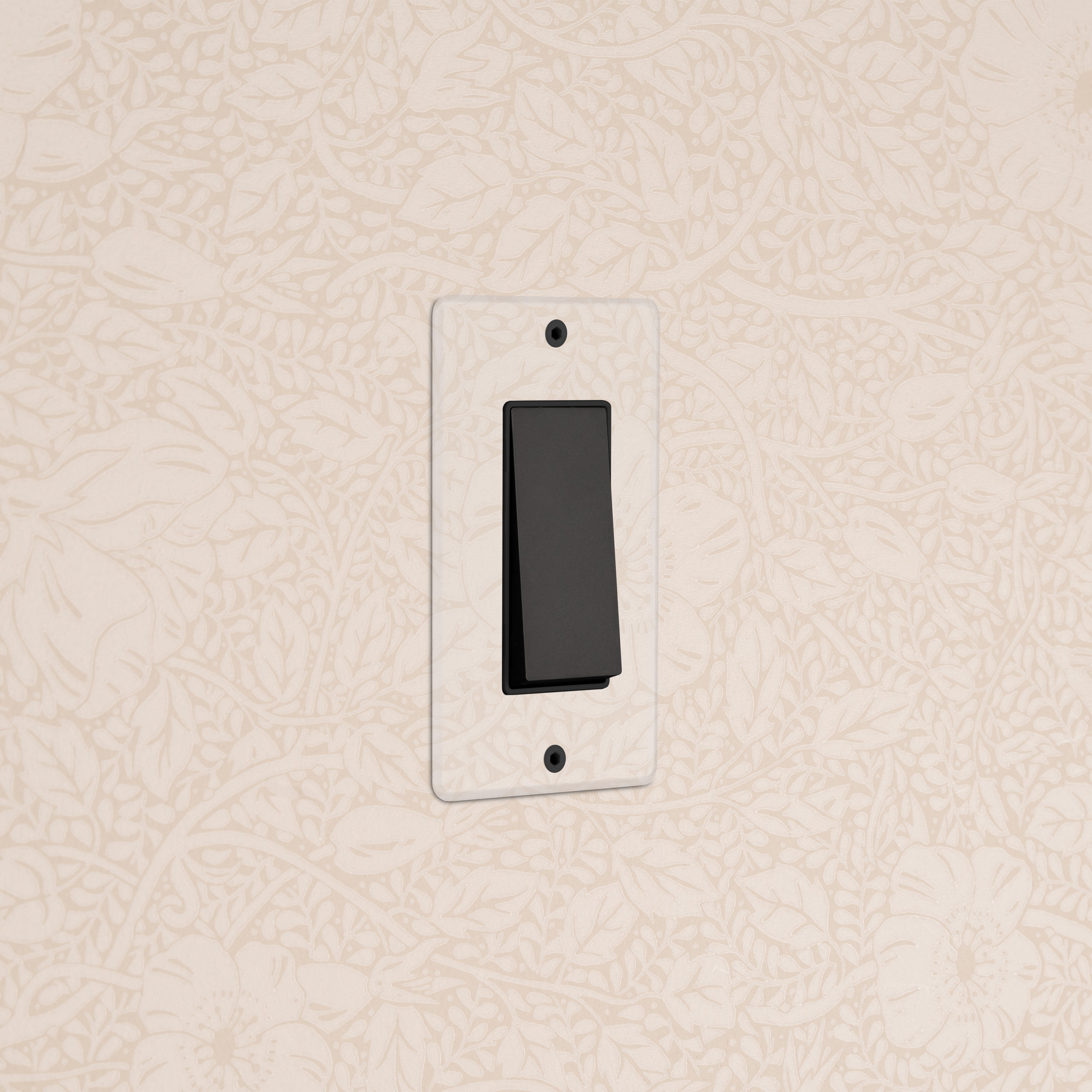 Kew 1G Four Way Rocker Switch in clear bronze black finish, installed on a wall with floral wallpaper.