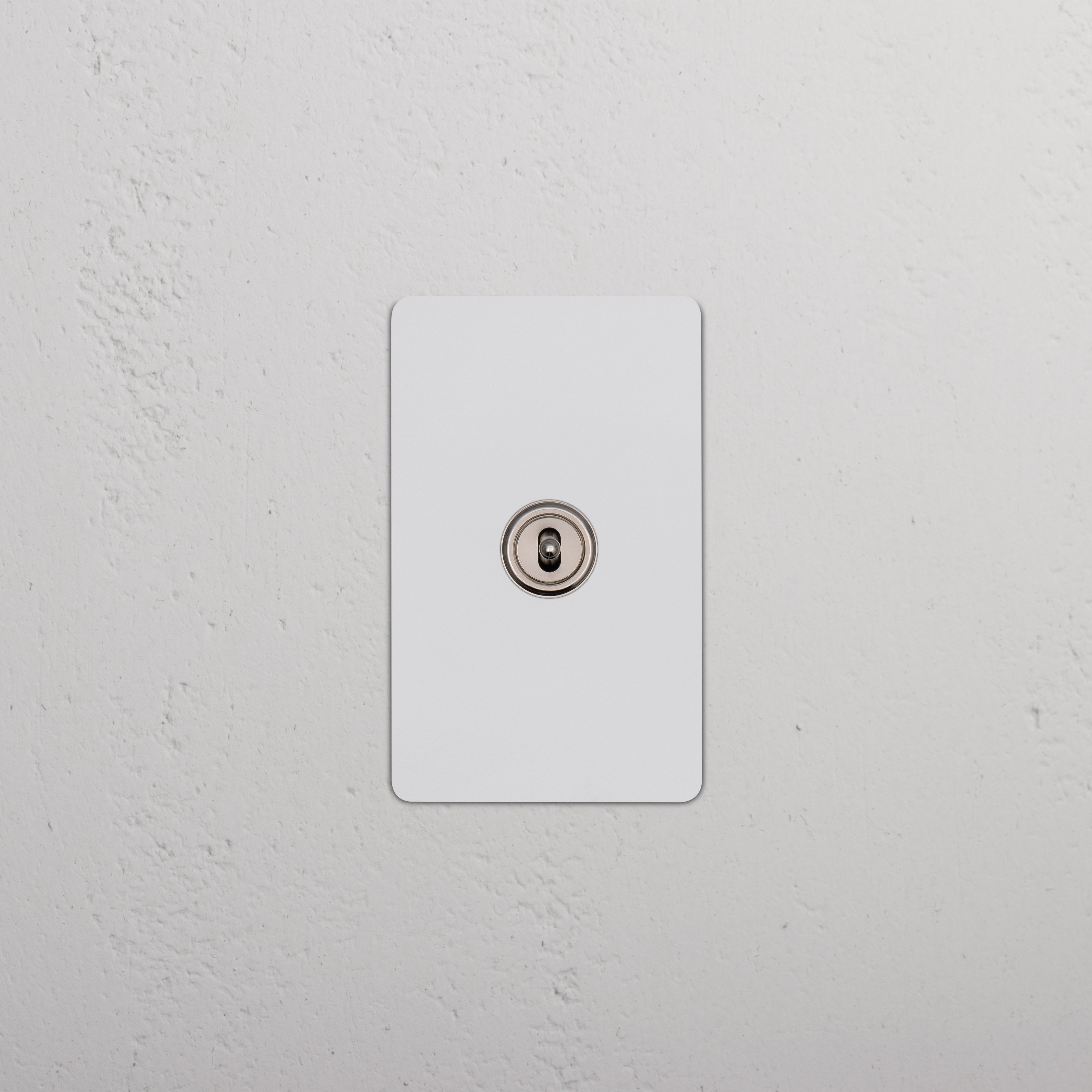 Kew 1G Center Retractive Toggle Switch in paintable polished nickel, single toggle on a white wall.