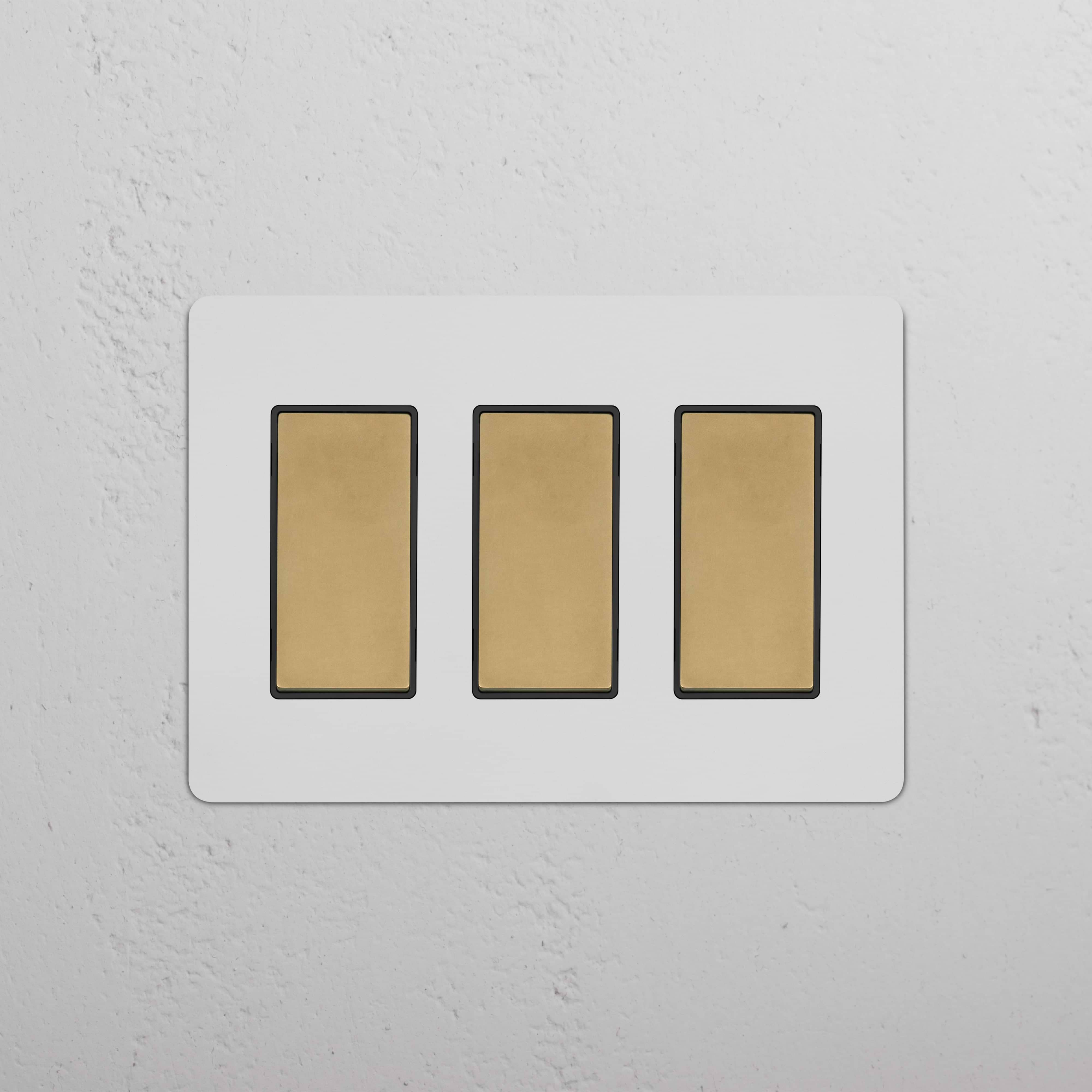 Kew 3G Rocker Switch in paintable antique brass black with three gold switches on a white plate.