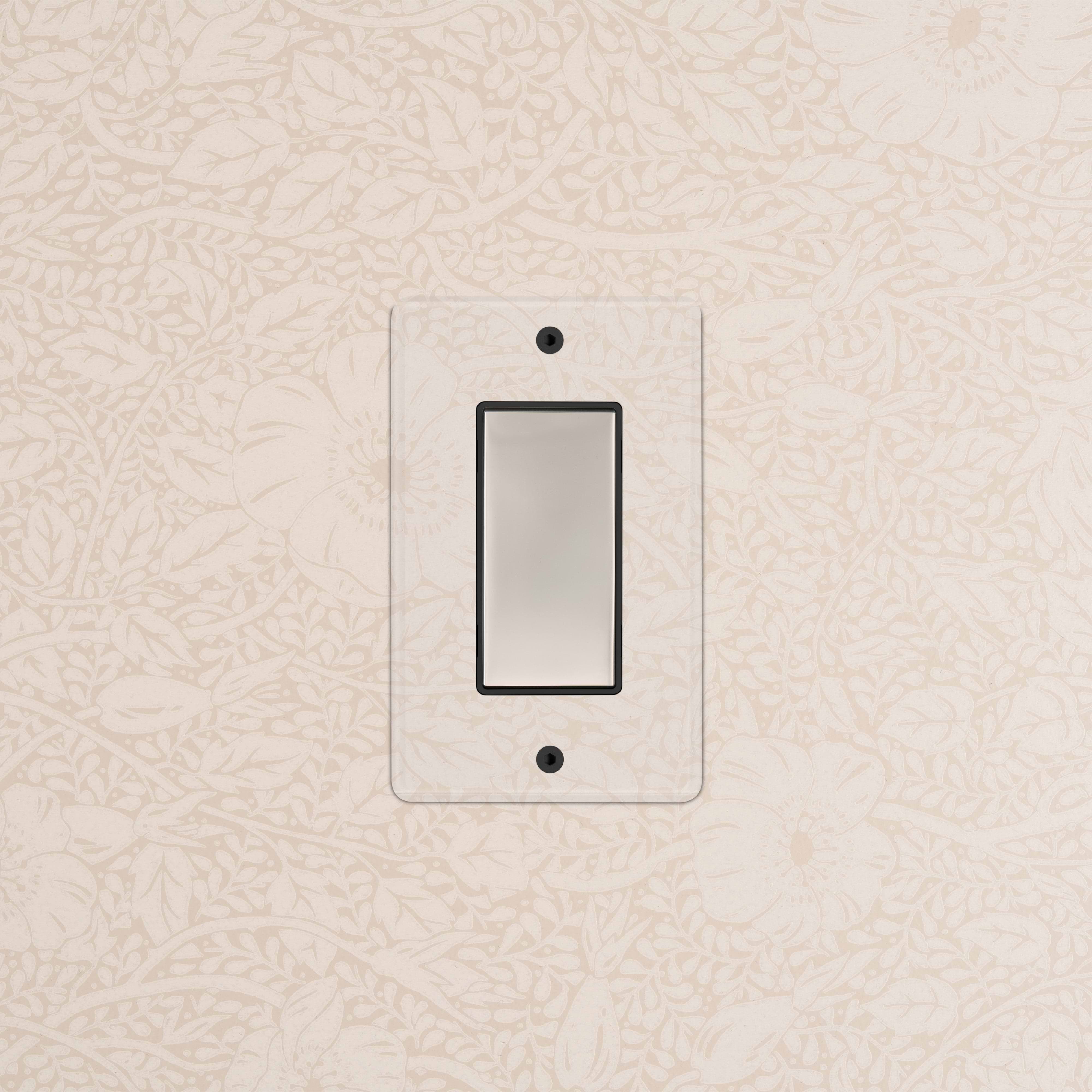 Kew 1G Center Retractive Rocker Switch in clear polished nickel black, mounted on patterned wallpaper.