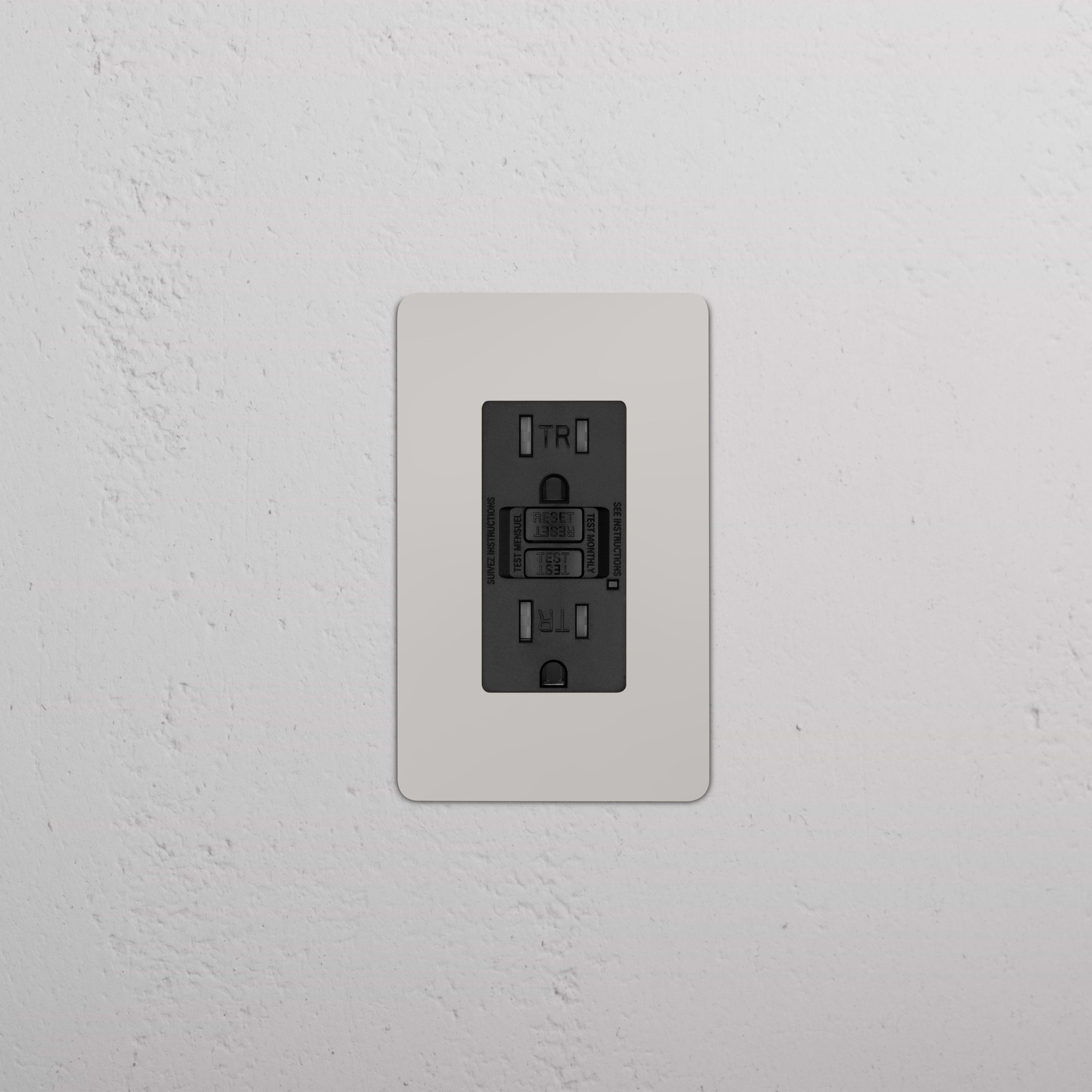 Kew 1G 15A GFCI Outlet in Polished Nickel Black with two sockets and test/reset buttons on a wall.
