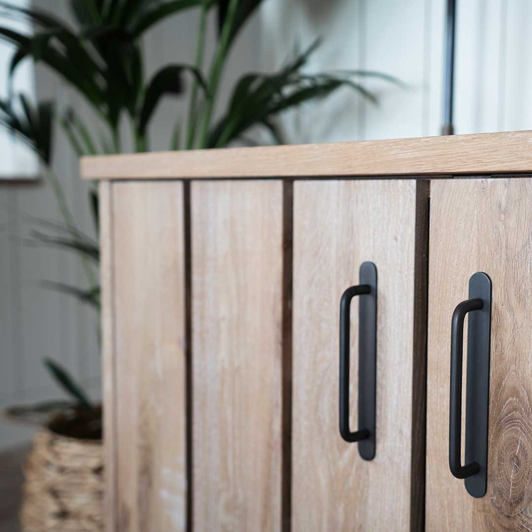 Close-up of Kilburn Furniture Handle Small in bronze, mounted on a light wooden cabinet drawer.