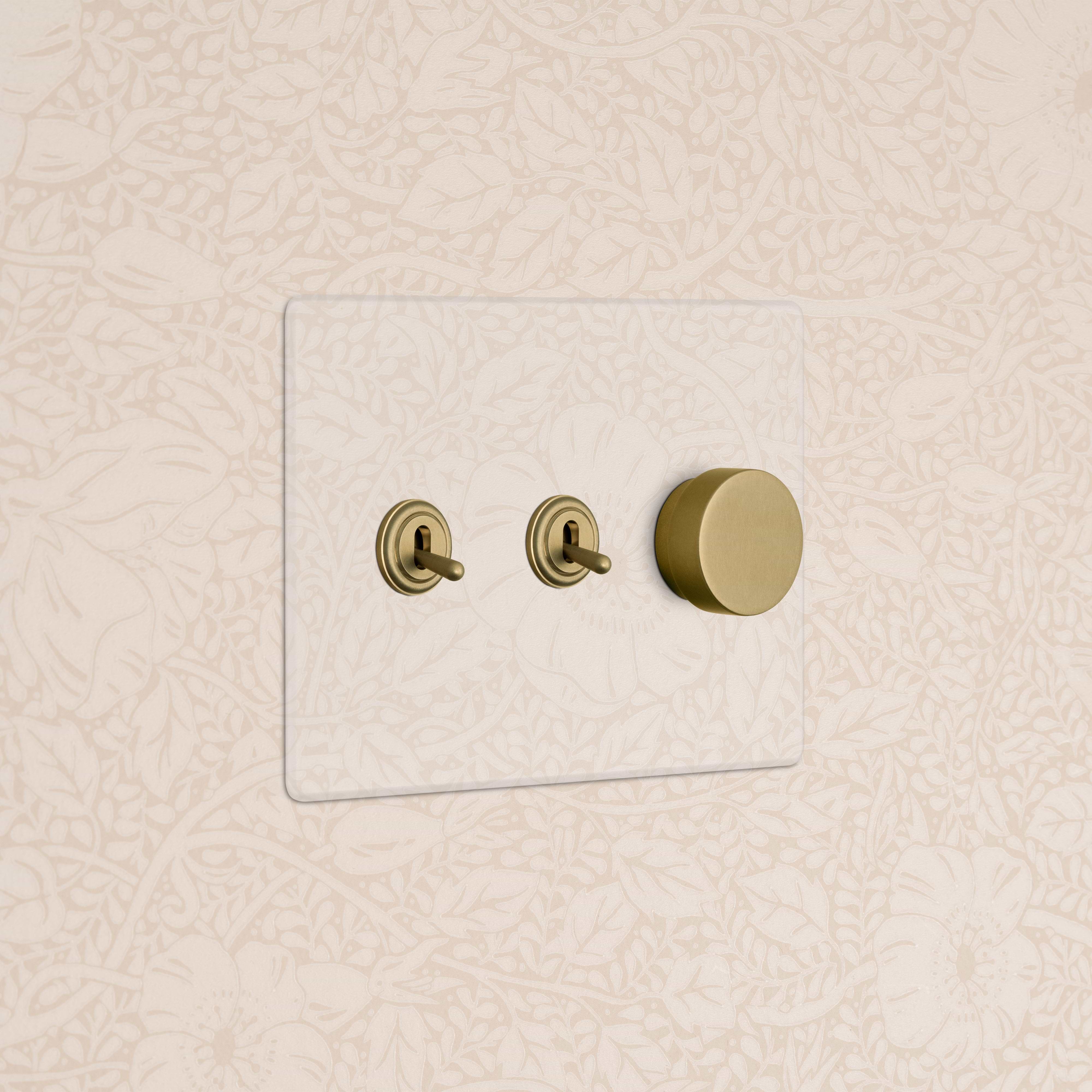 Kew 3G 2x Toggle & Dimmer Switch in Clear Antique Brass with two toggles and one dimmer, wall-mounted.