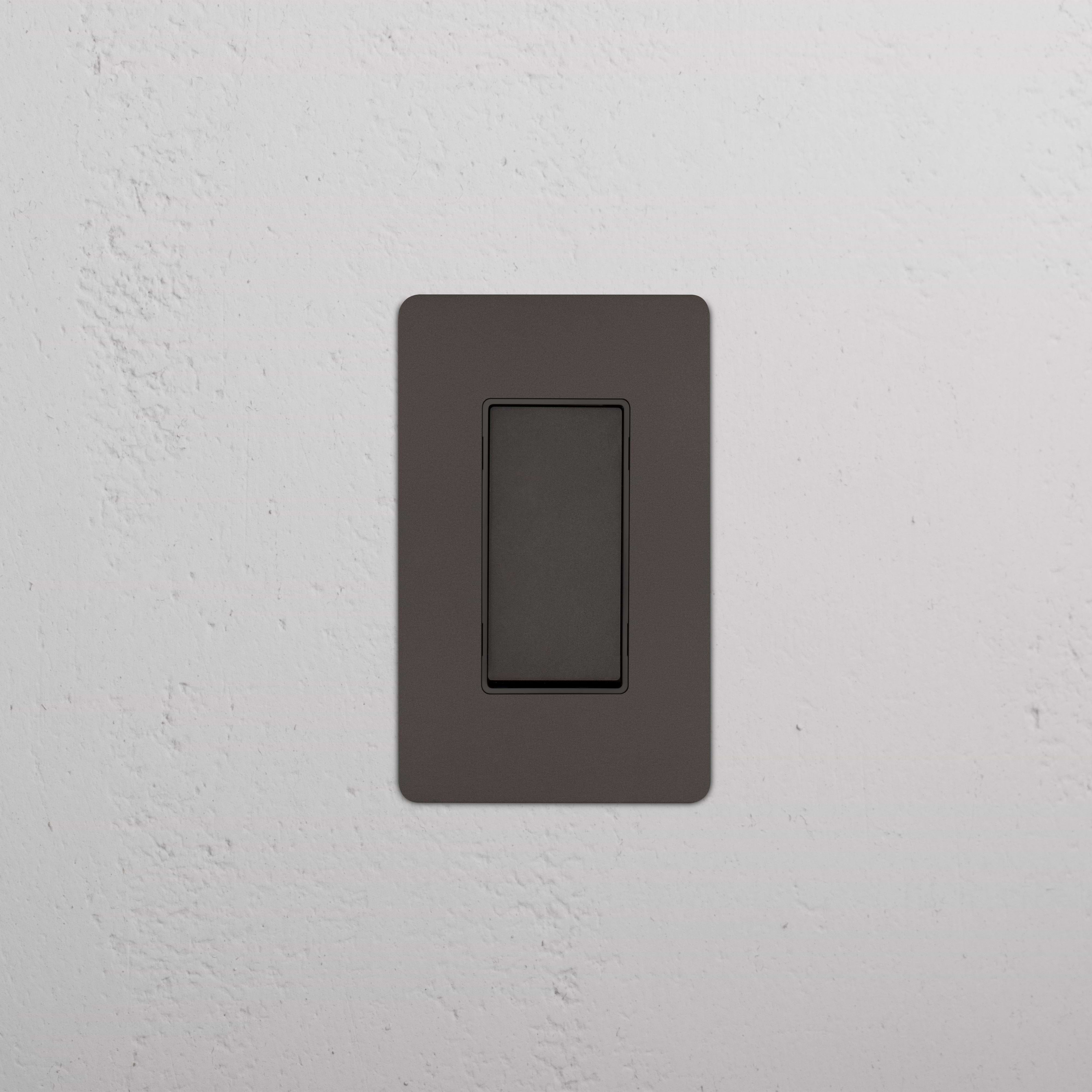 Bronze Black Kew 1G Smart Retractive Rocker Switch installed on a white textured wall.