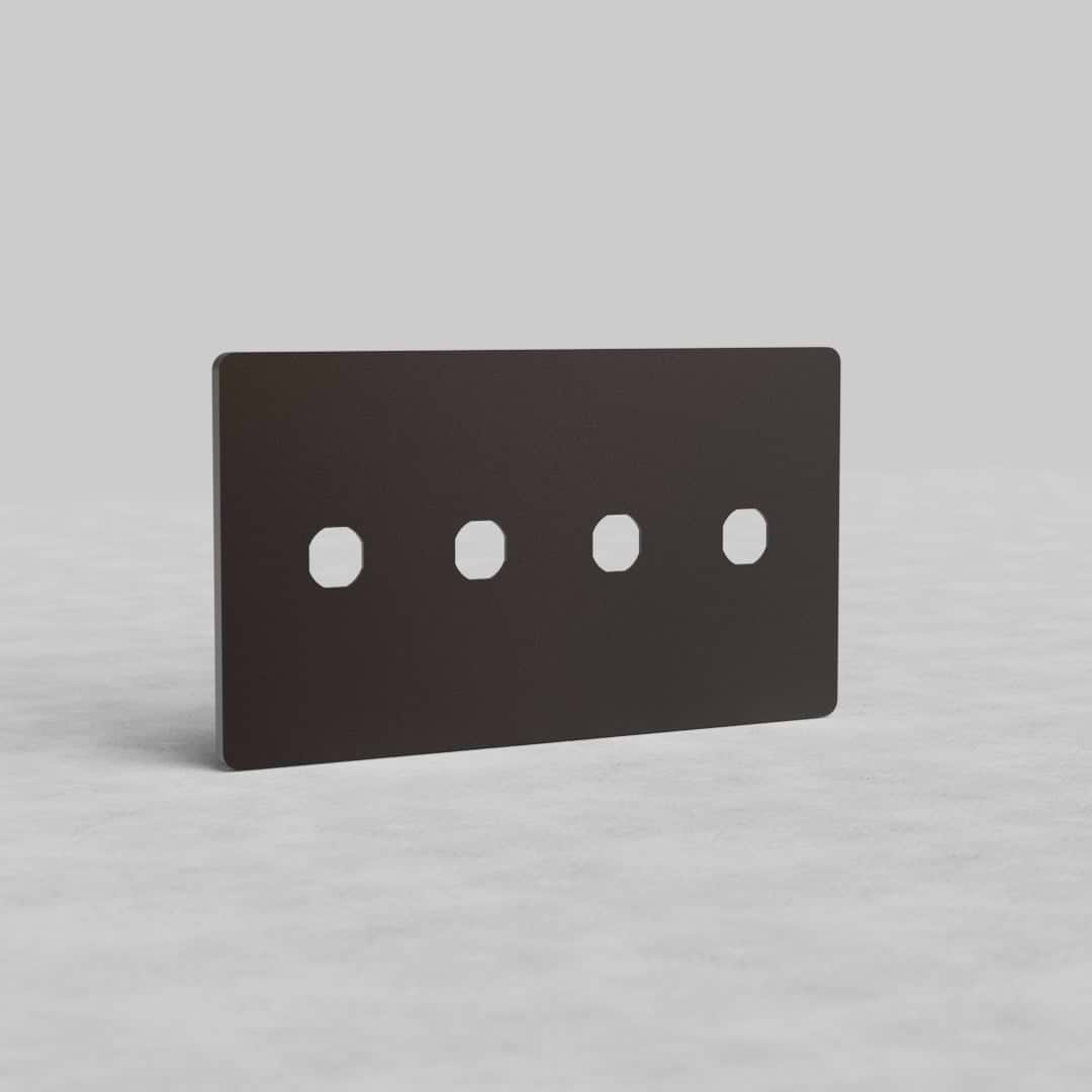 Bronze 4-gang switch plate, Grove US design, with four square cutouts, shown upright on a gray surface.