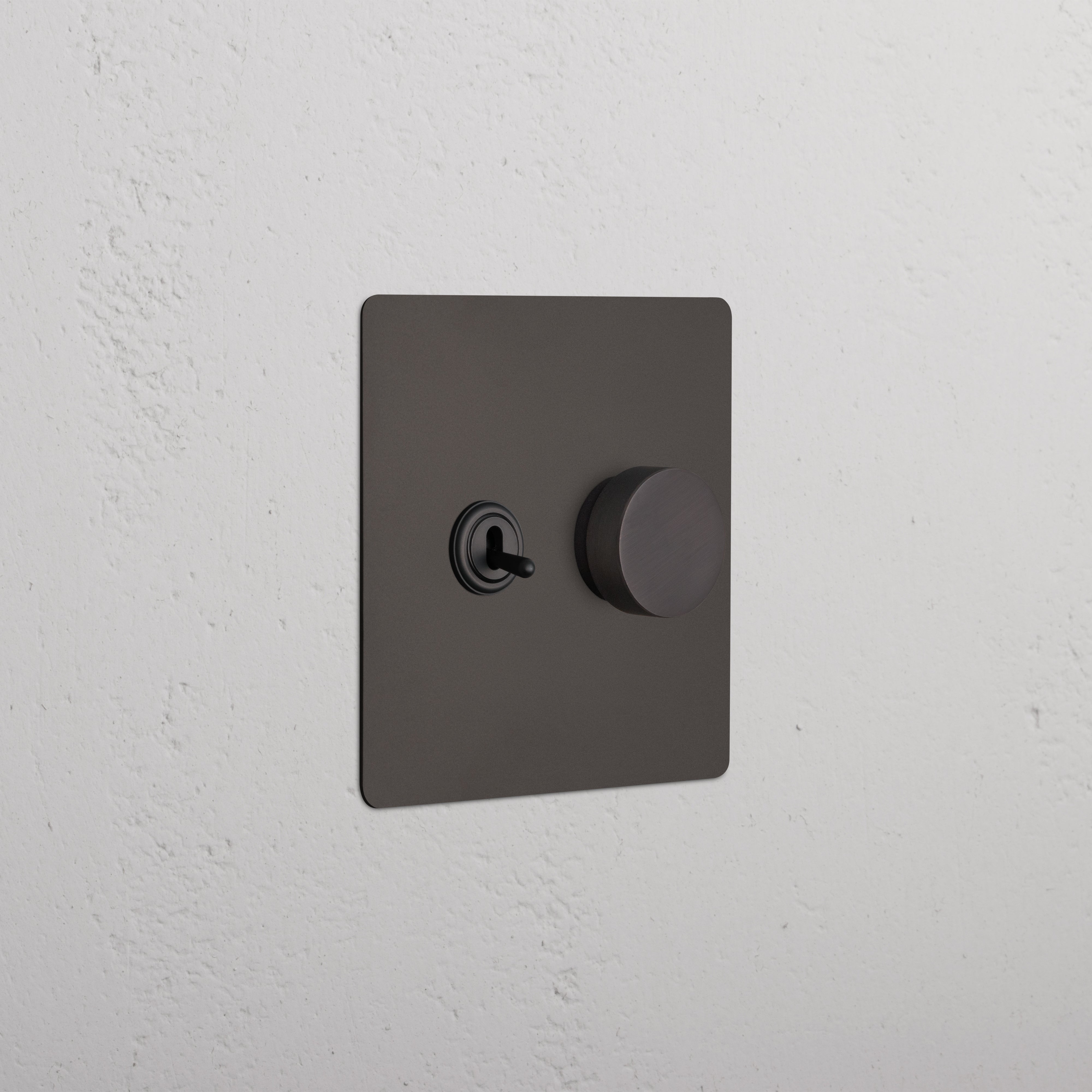 Bronze Kew 2G Toggle & Dimmer Switch with left toggle and right dimmer knob, shown on a white wall.