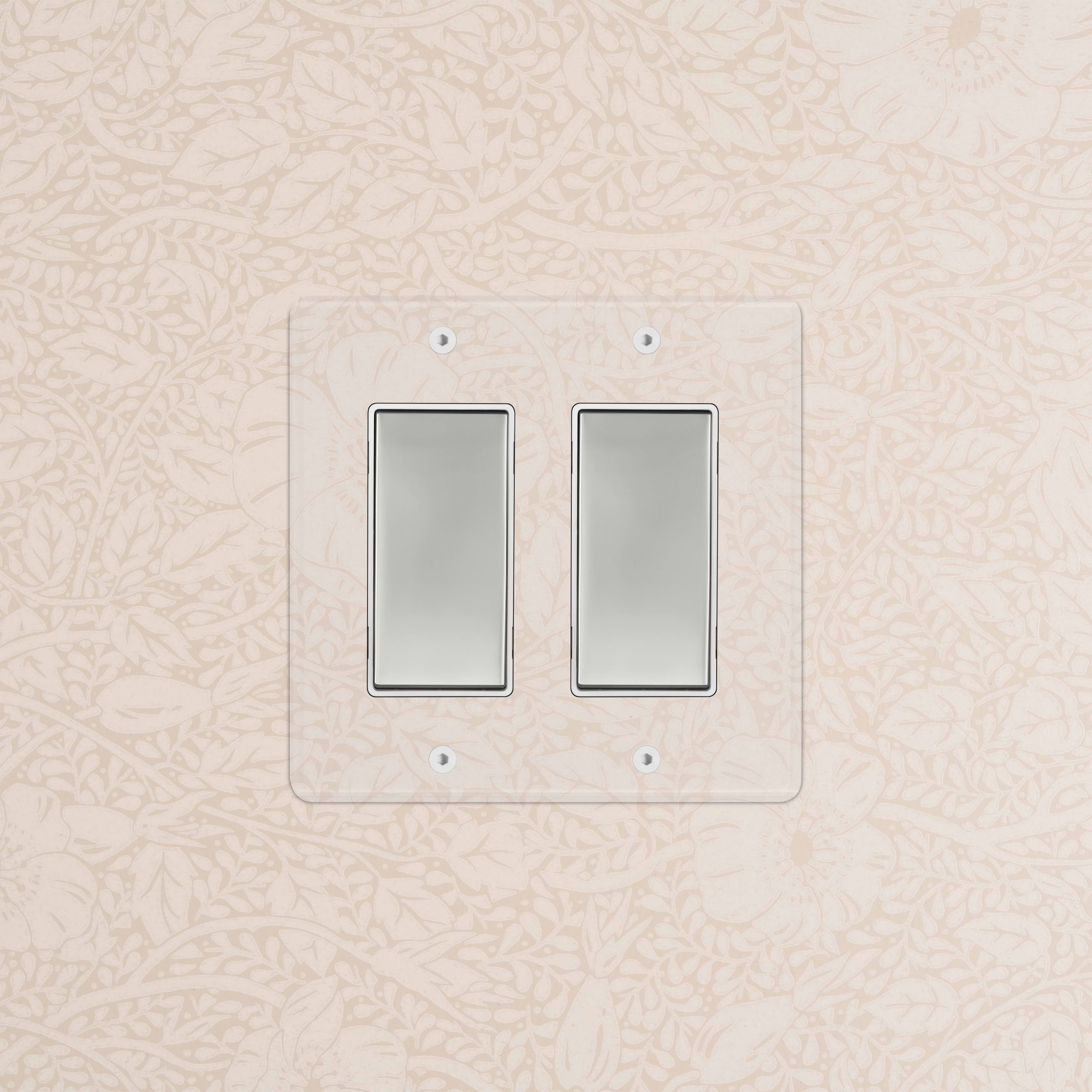 Kew 2G Rocker Switch in clear polished nickel white finish, installed on a wall with floral wallpaper.