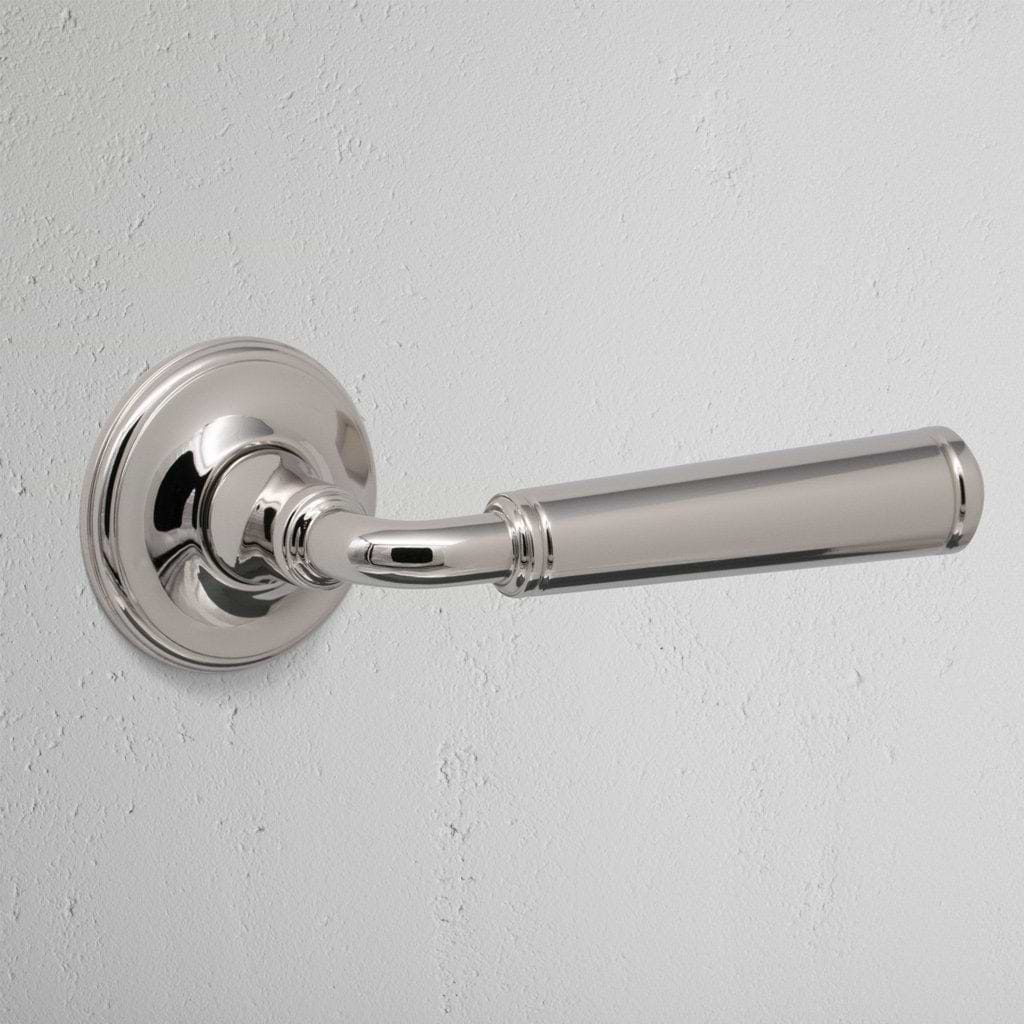 Close-up of Digby Passage Door Handle Unsprung in polished nickel finish, mounted on a white wall.