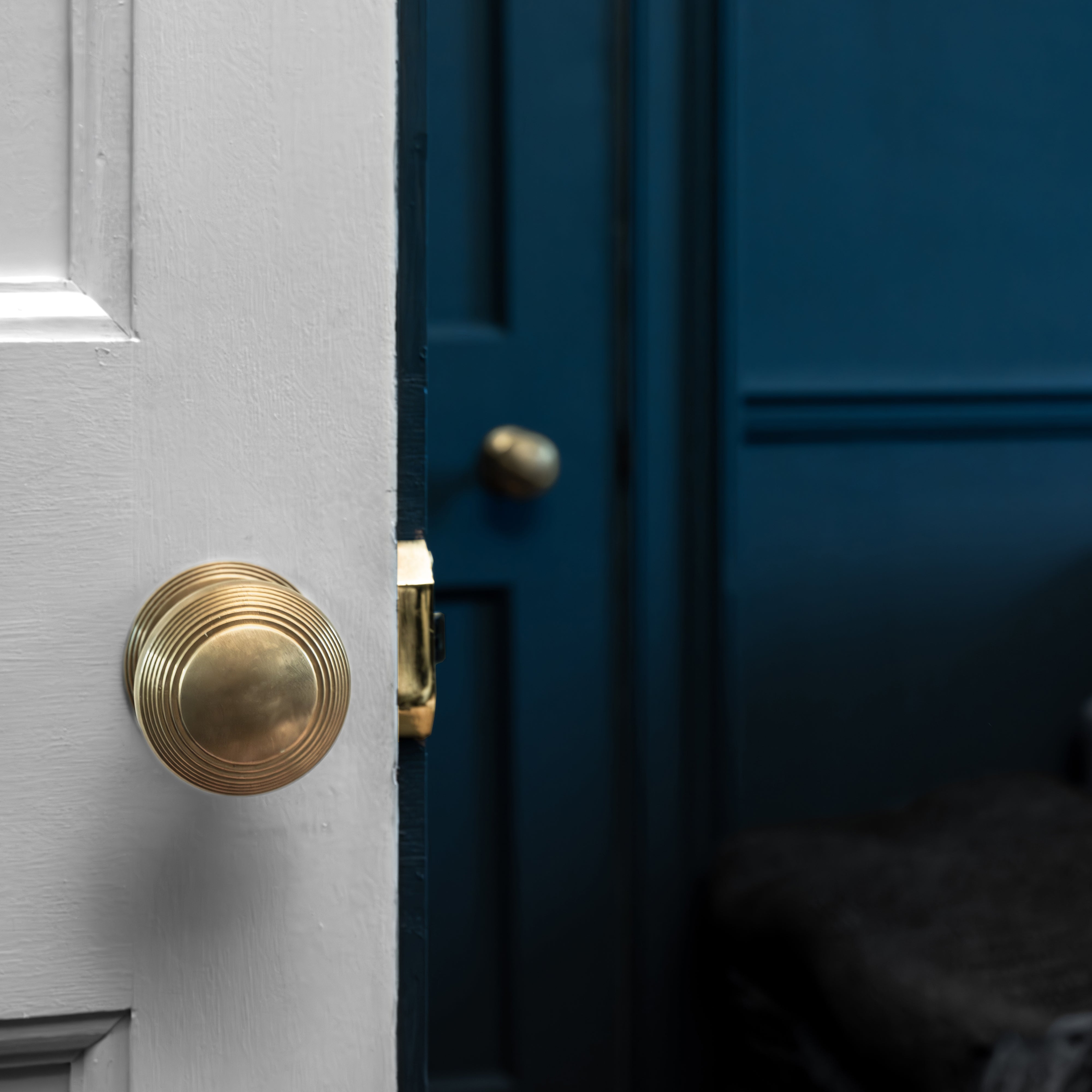 Antique brass Poplar Passage Door Knob Set installed on a white door, partially open.