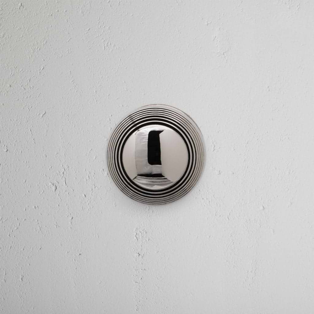 Poplar Dummy Door Knob Set in polished nickel with circular ridges, mounted on a white textured wall.