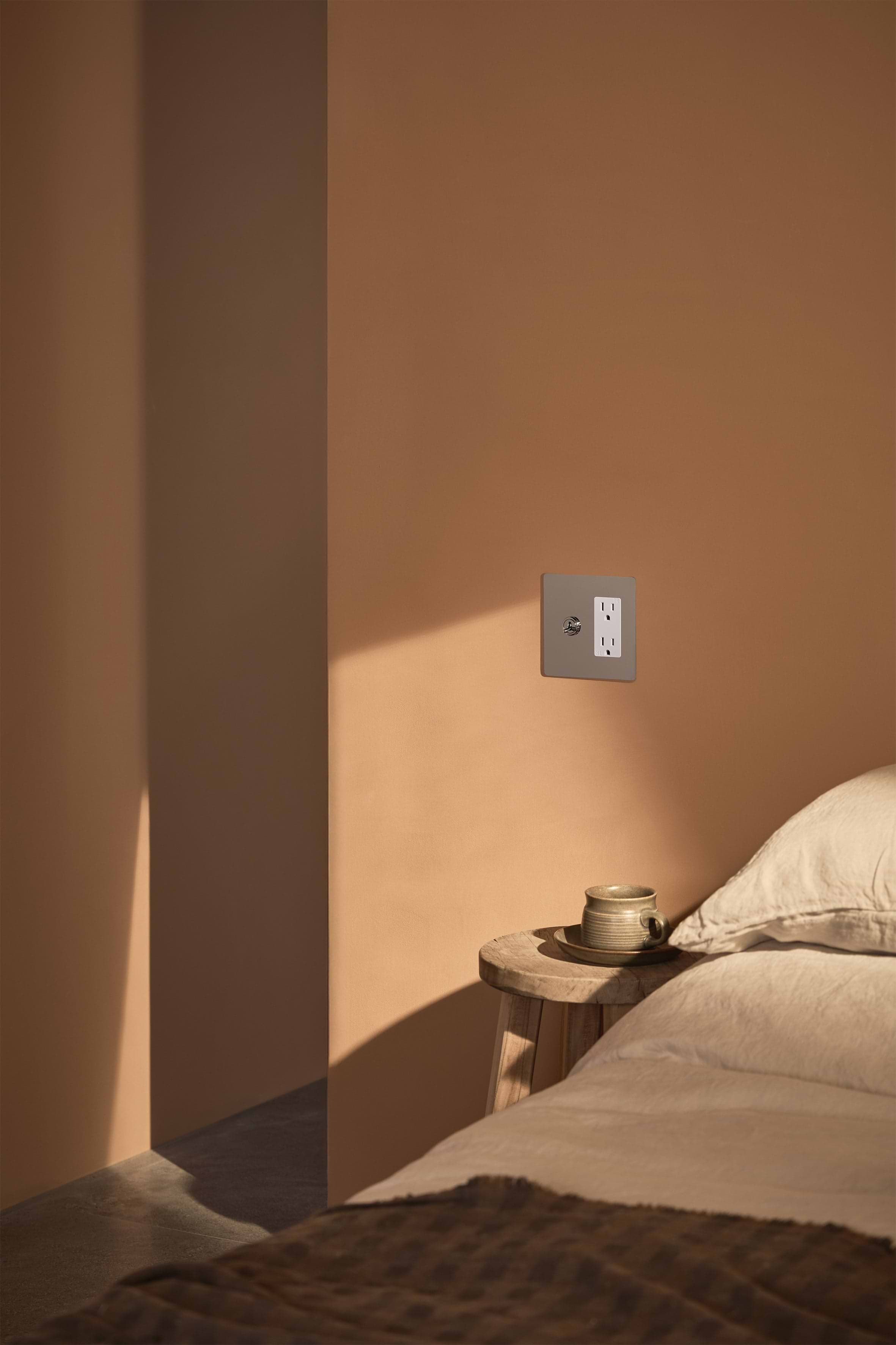 Kew 2G Toggle Switch & Outlet in Polished Nickel White mounted on a wall, showing toggles and outlet.