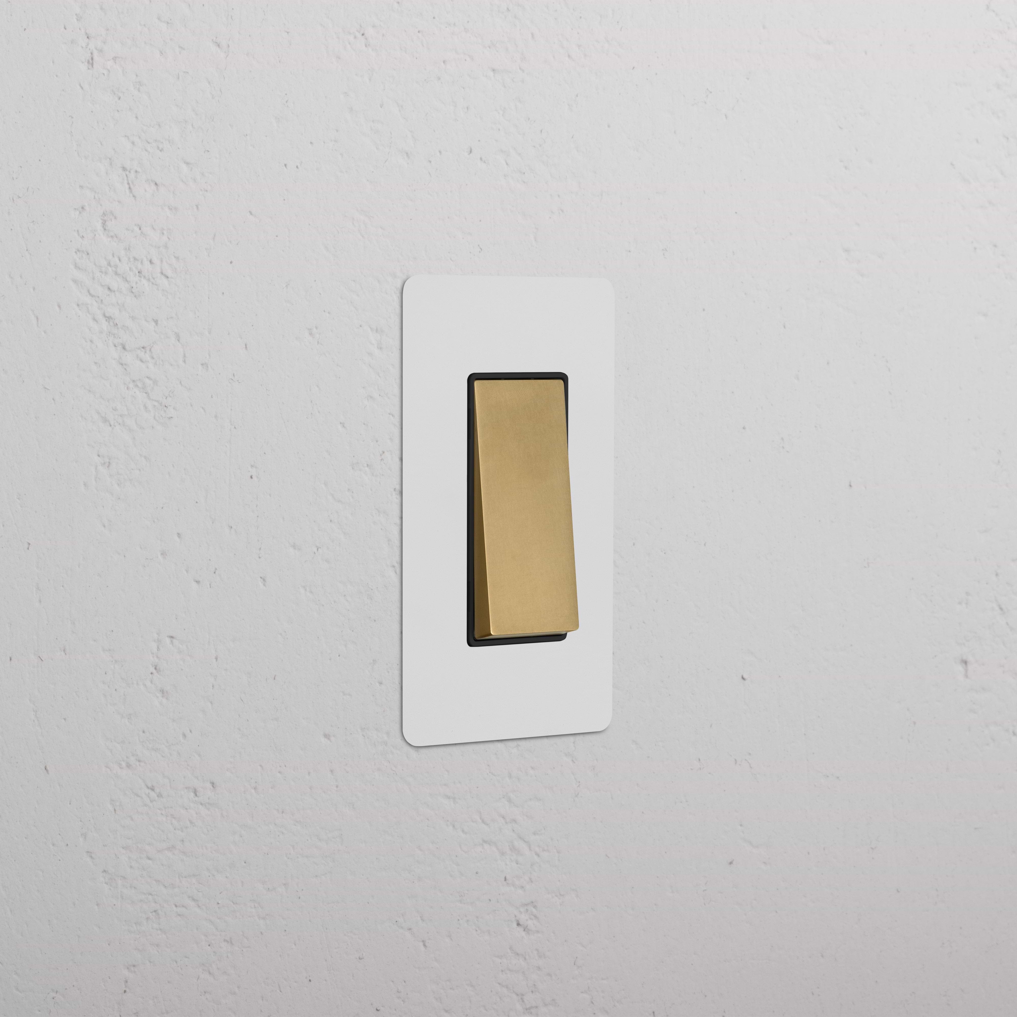 Kew 1G Retractive Rocker Switch in paintable antique brass black, shown mounted on a textured white wall.