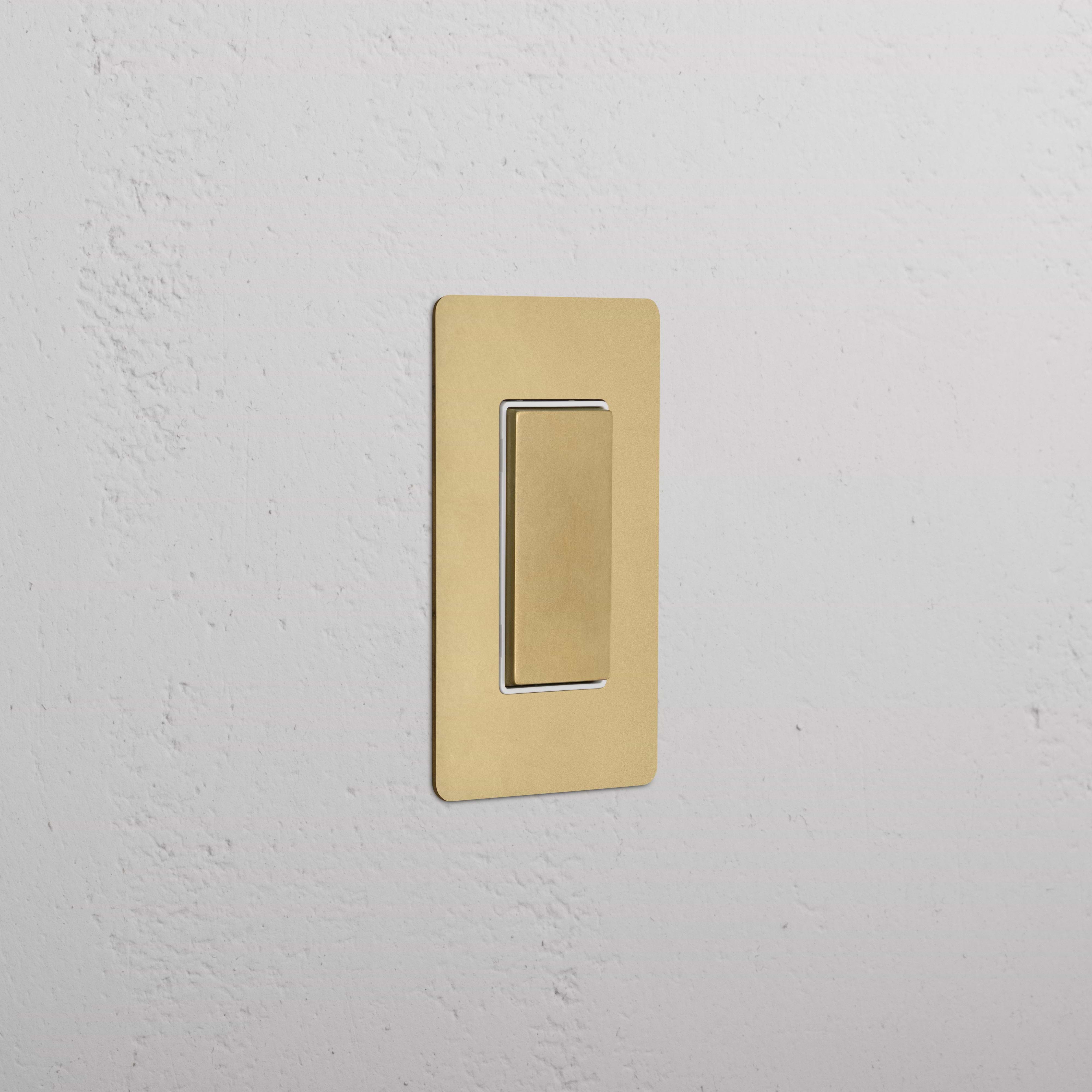 Kew 1G Center Retractive Rocker Switch in Antique Brass White mounted on a white wall.