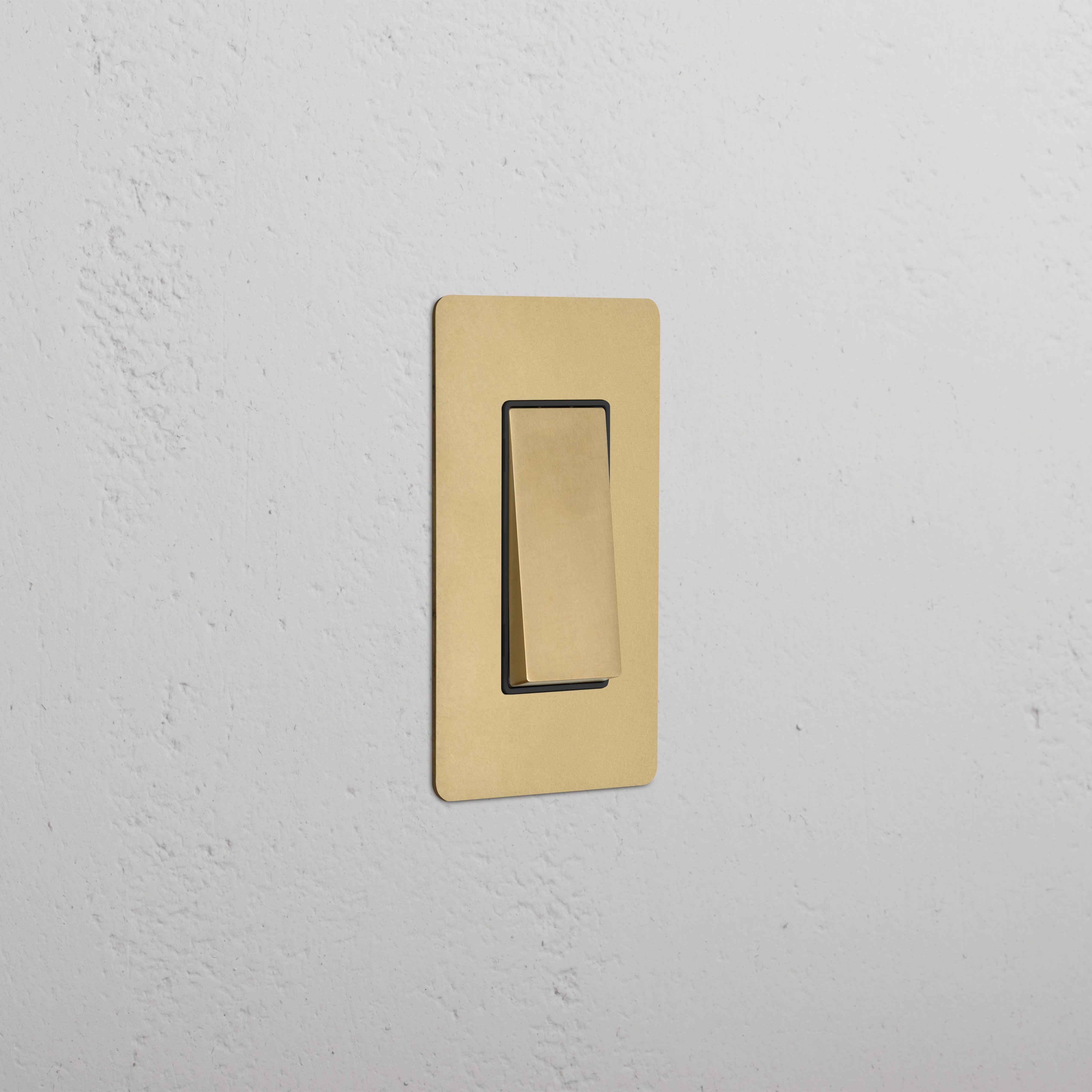 Kew 1G Retractive Rocker Switch in antique brass black, shown mounted on a white textured wall.
