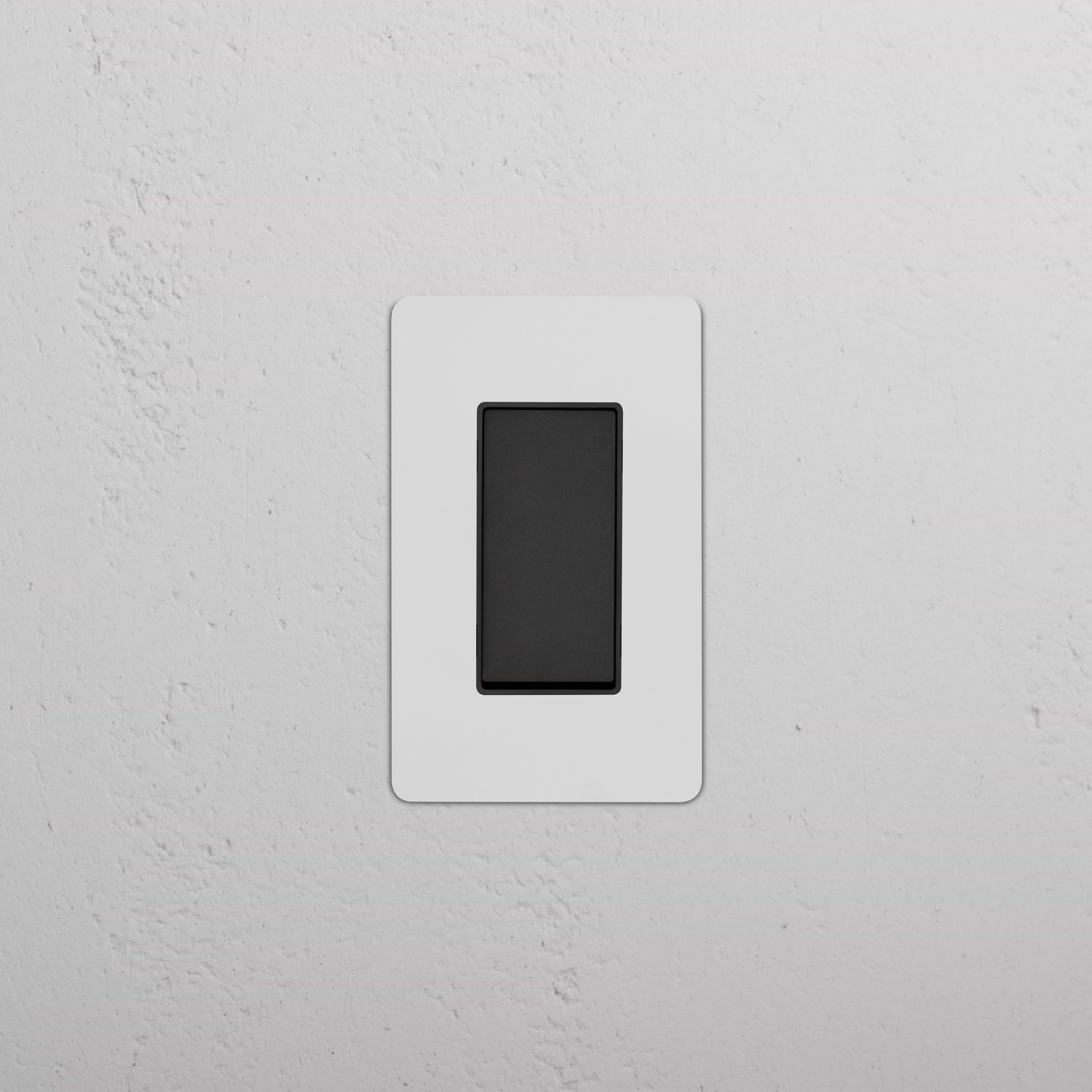 Kew 1G Retractive Rocker Switch in paintable bronze black with a white faceplate on a white wall.