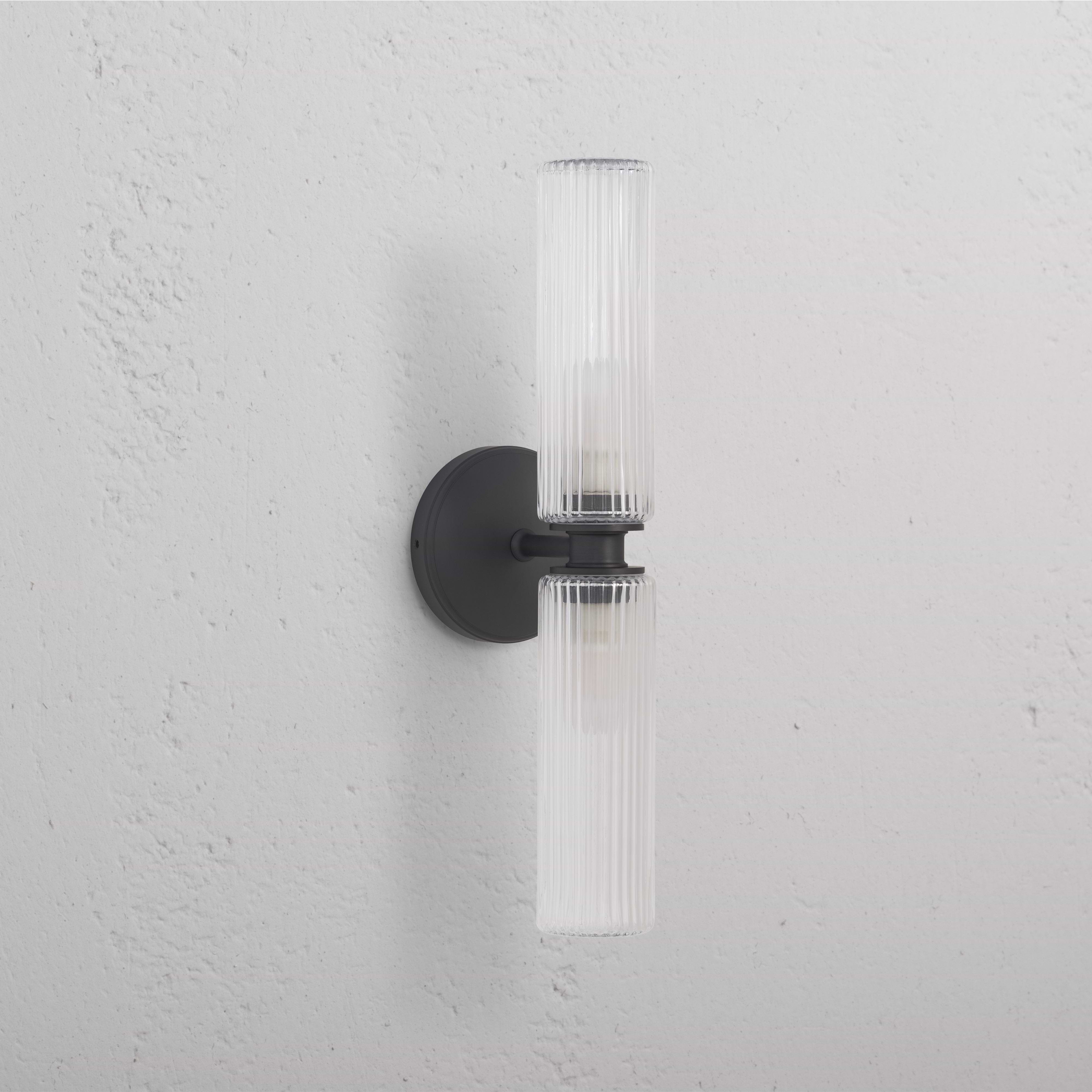 Claremont Medium Wall Light with fluted glass shades and bronze finish, mounted on a white wall.