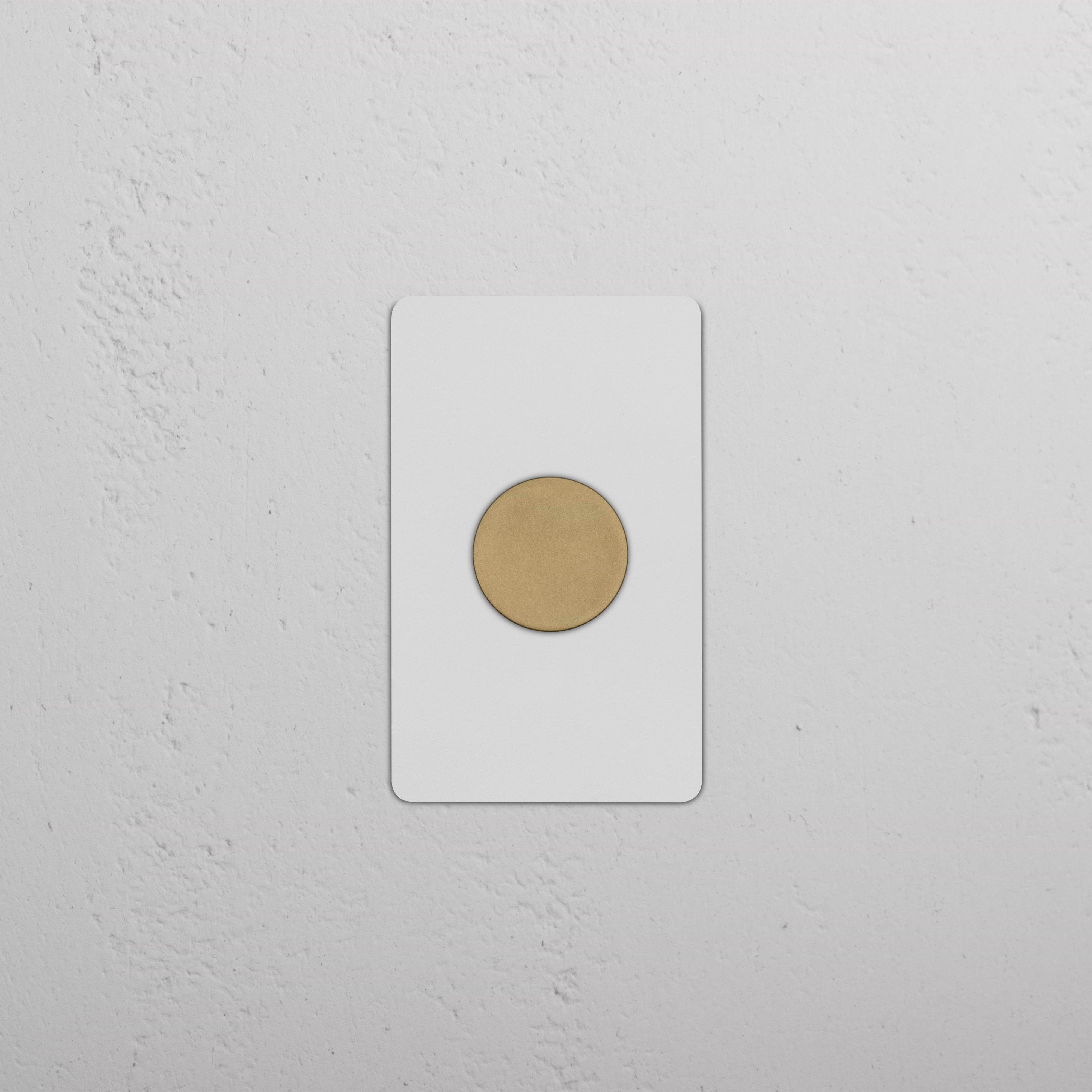 Kew 1G Dimmer Switch in paintable antique brass finish, mounted on a textured white wall.