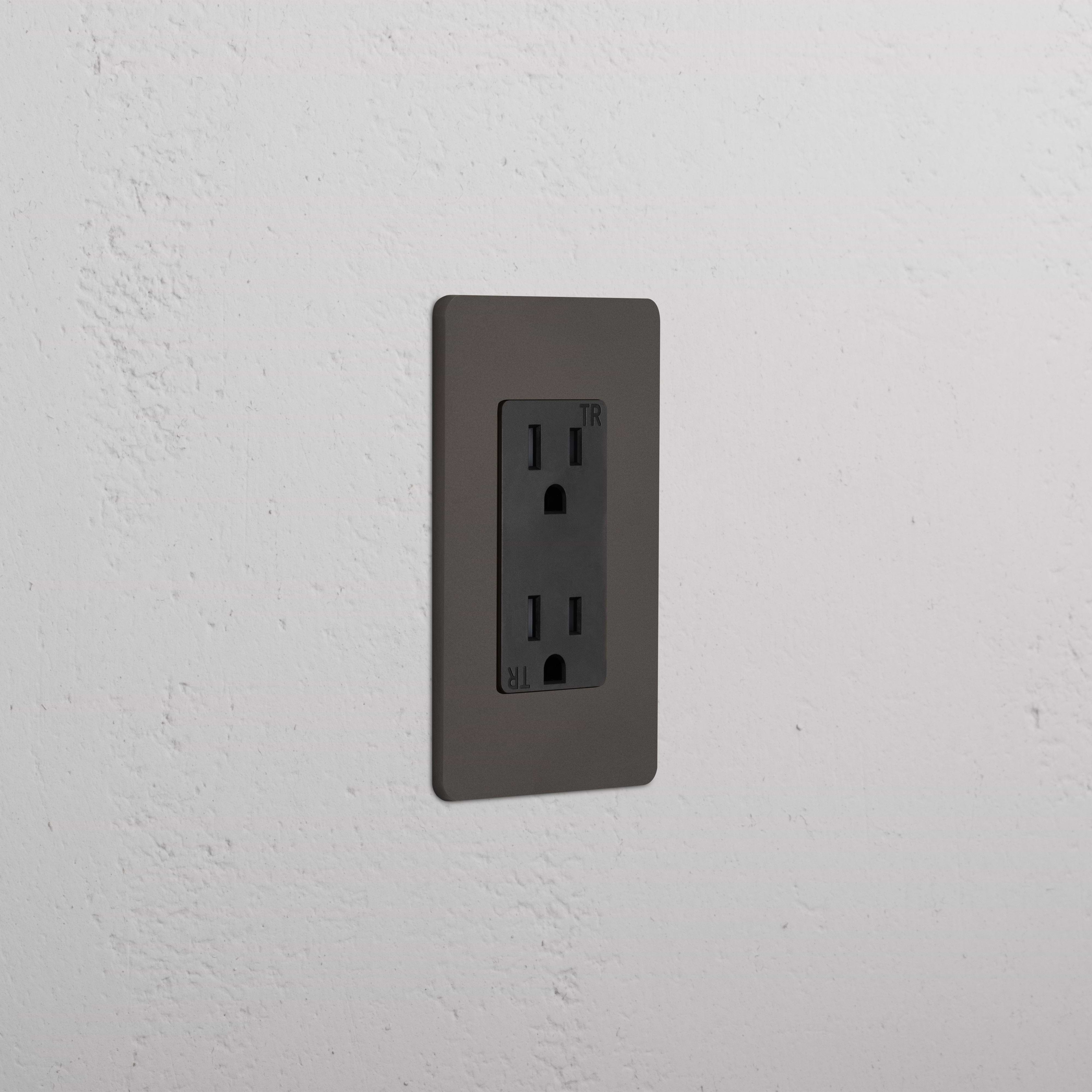 Grove 1G 15A electrical outlet in Bronze Black, single-gang design, installed on a white textured wall.