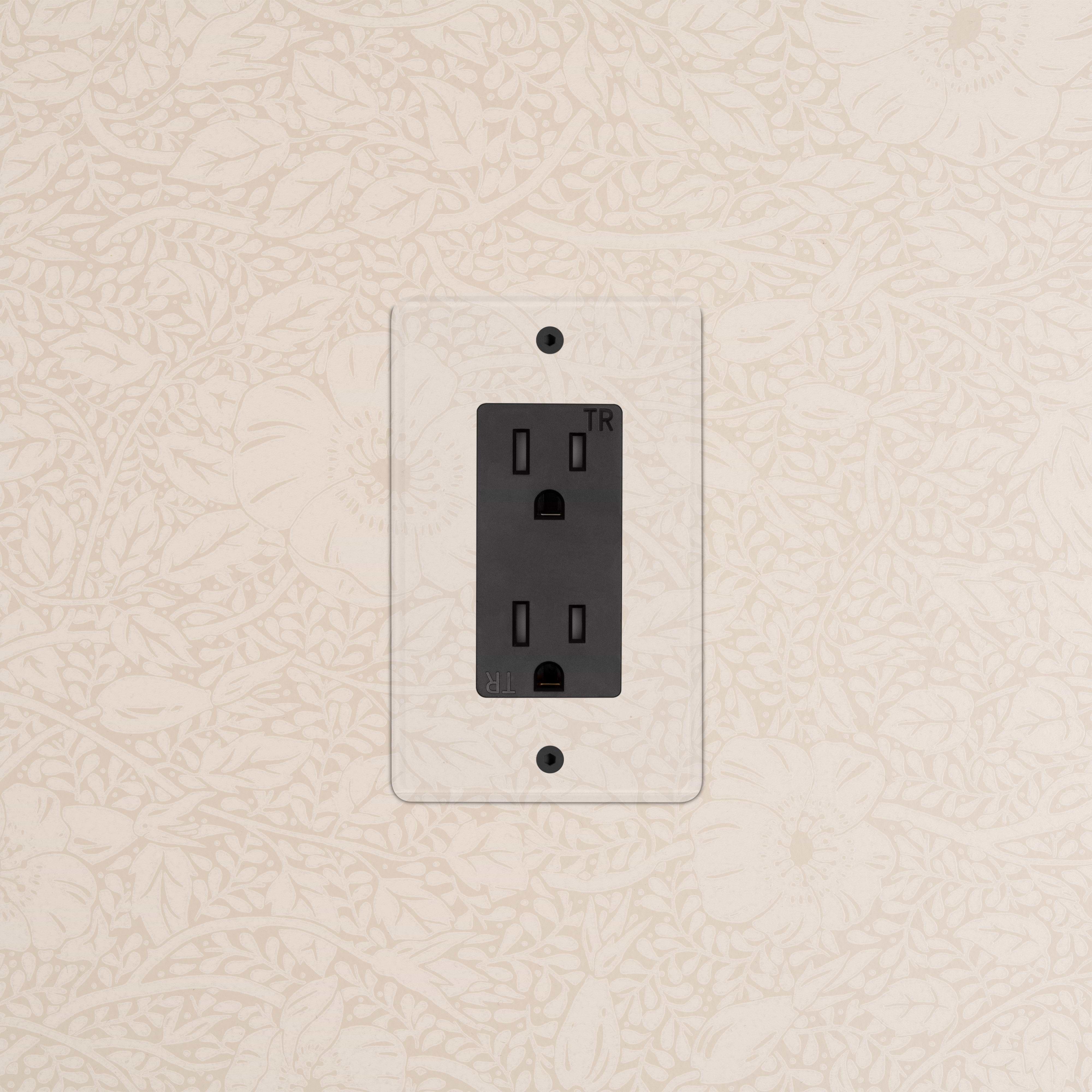 Kew 1G 15A Outlet in Clear Black finish with transparent cover, mounted on a patterned beige wall.