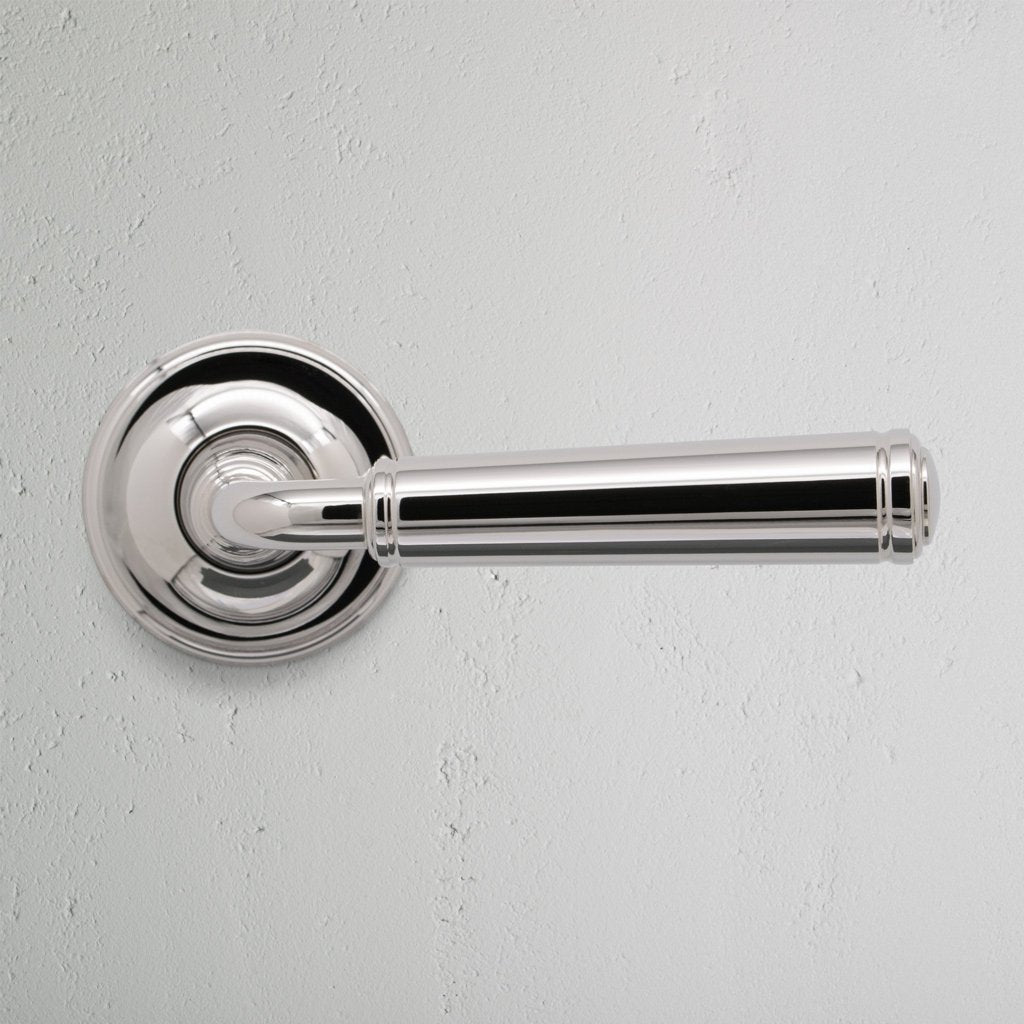 Digby Passage Door Handle Unsprung in polished nickel, shown mounted on a round base plate against a white wall.