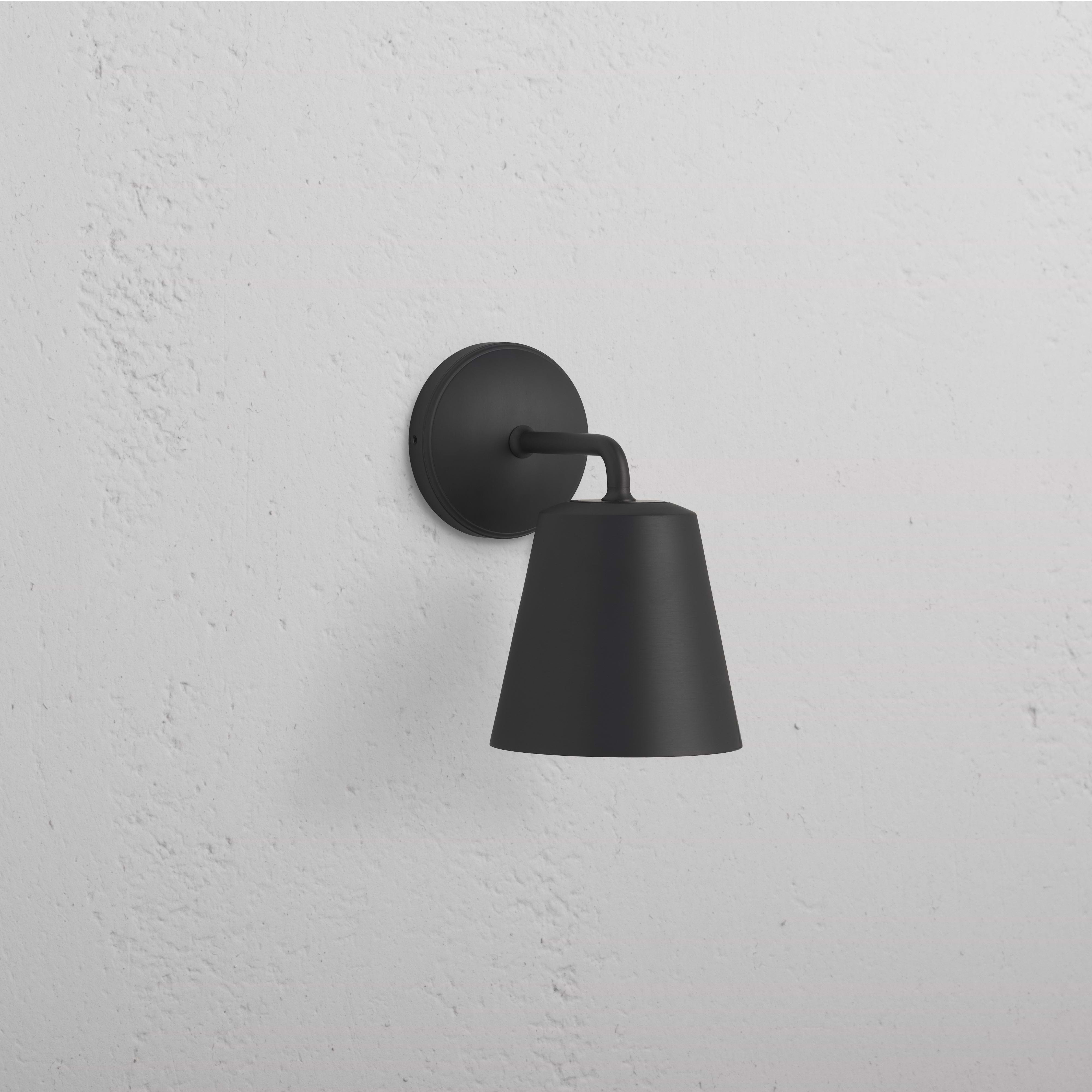 Richmond Medium Wall Light in bronze finish with a conical shade, mounted on a white wall.