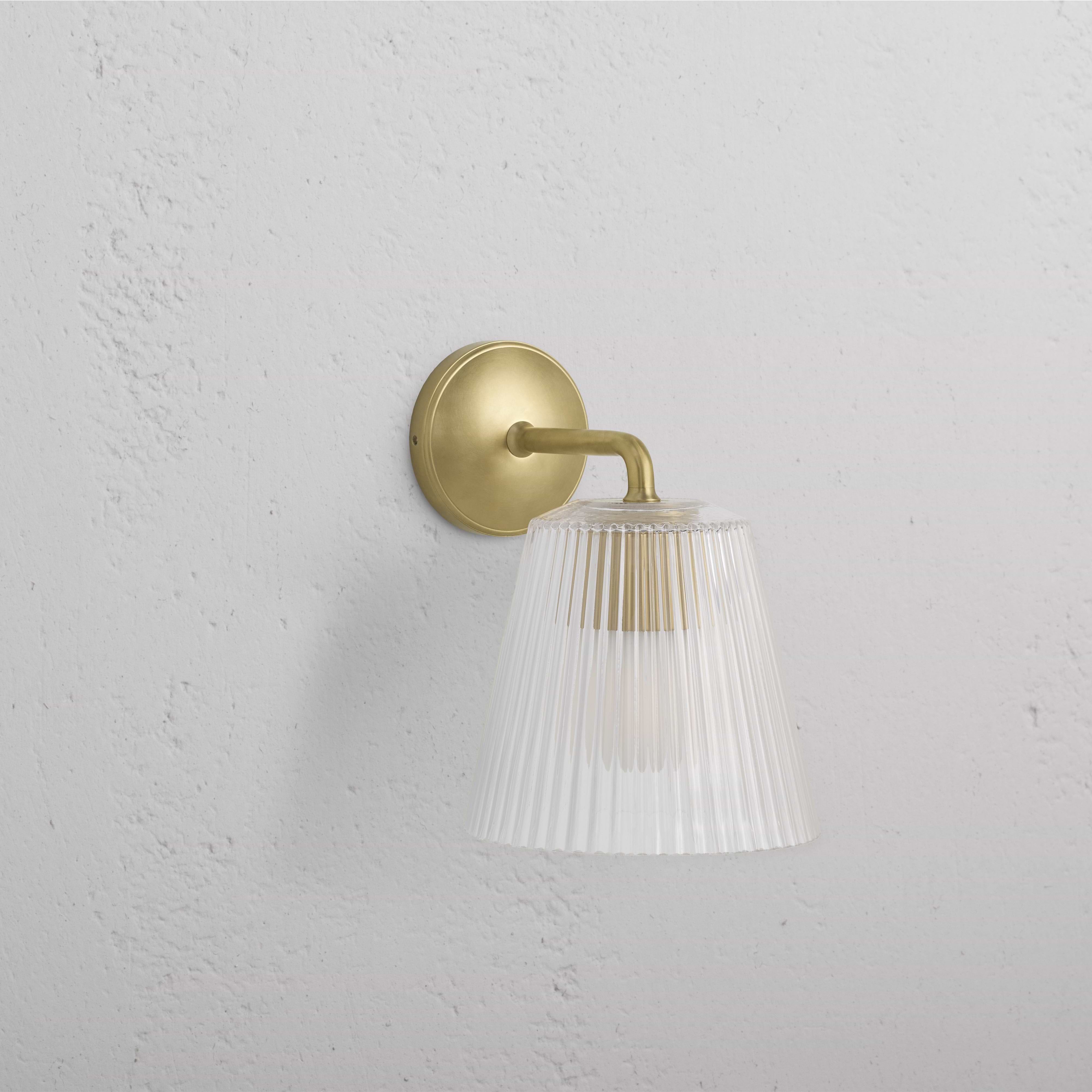 Large Richmond Wall Light in Antique Brass with clear fluted glass shade, mounted on a white wall.