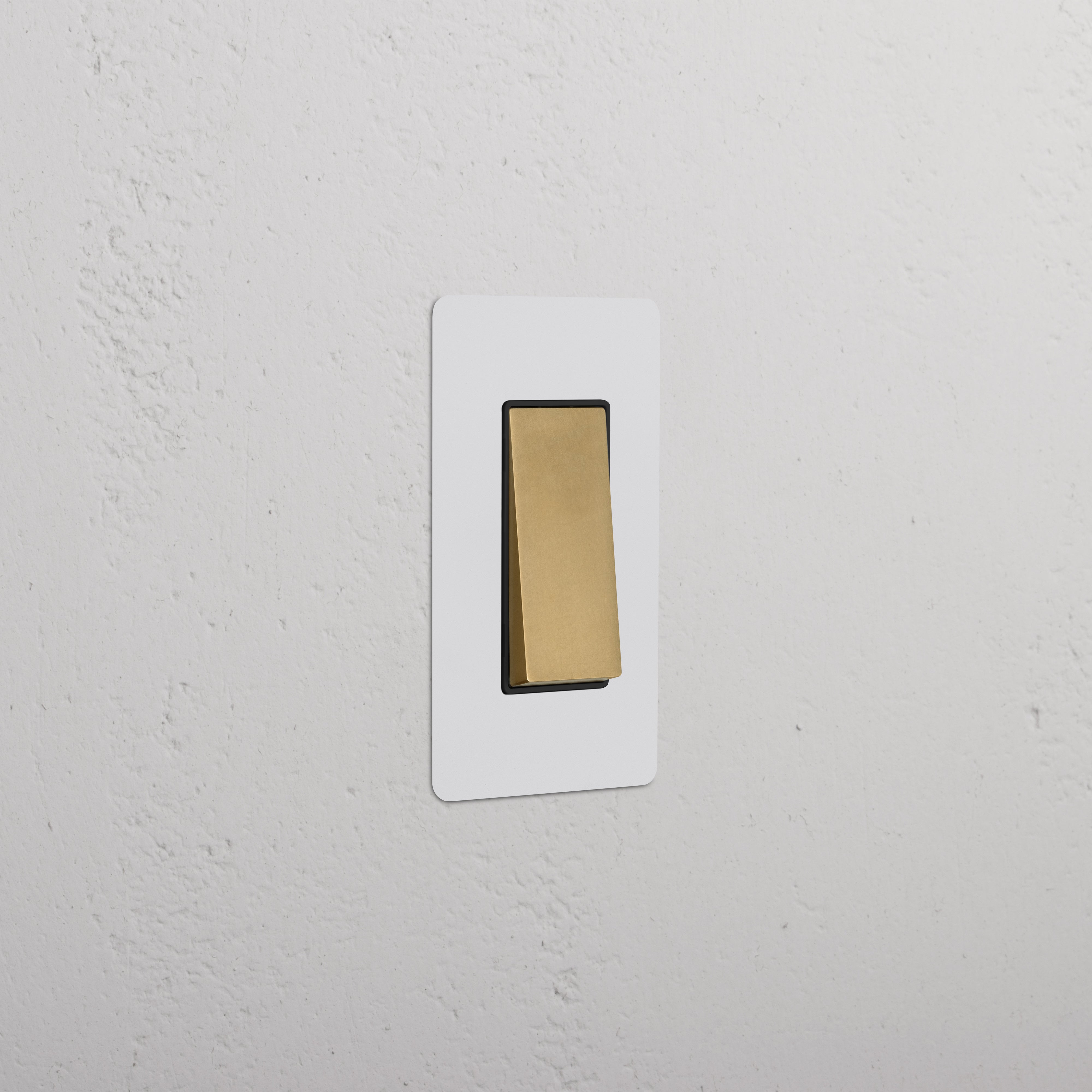 Kew 1G Retractive Rocker Switch in paintable antique brass black, shown mounted on a textured white wall.