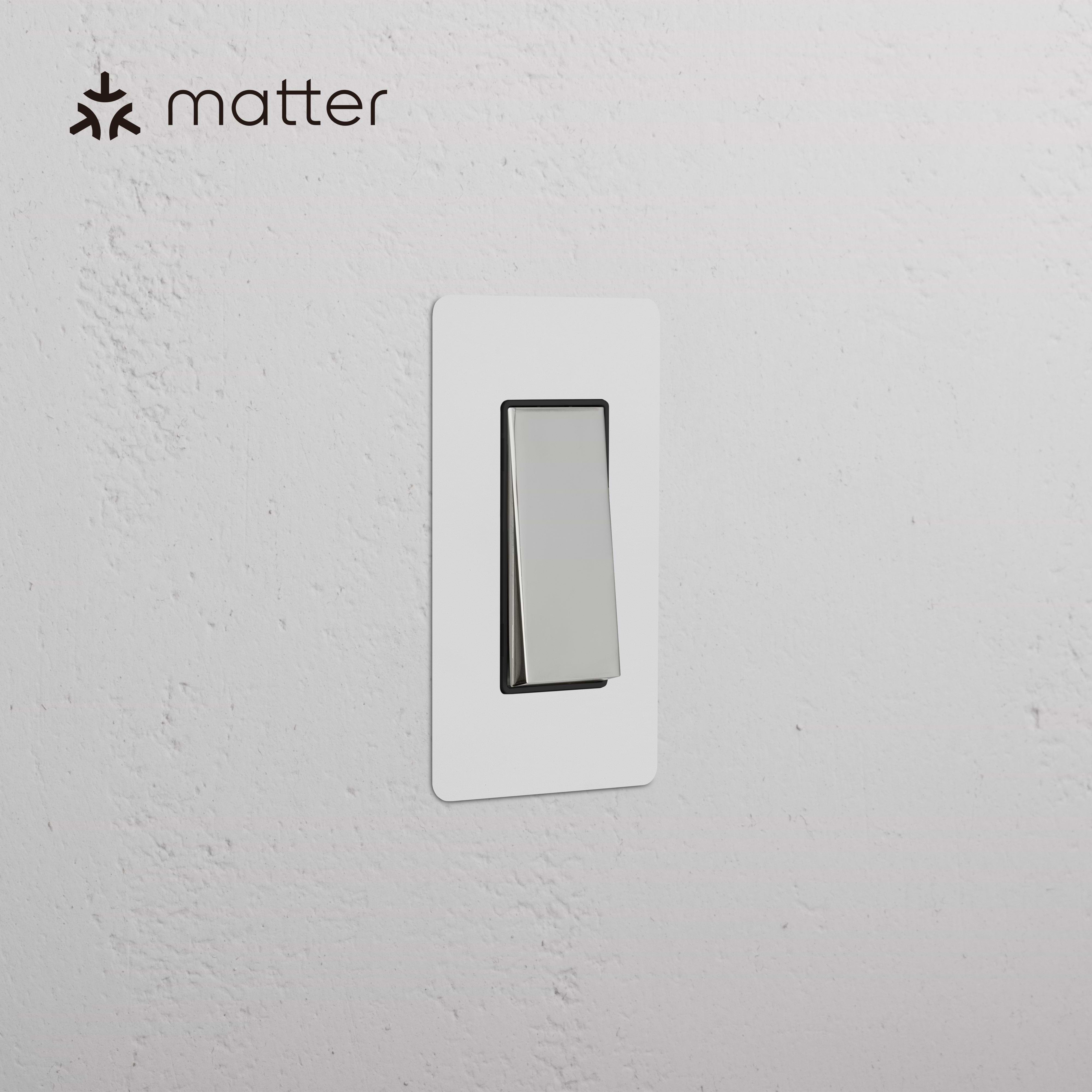 Kew 1G Smart Retractive Rocker Switch in paintable polished nickel black finish, mounted on a wall.