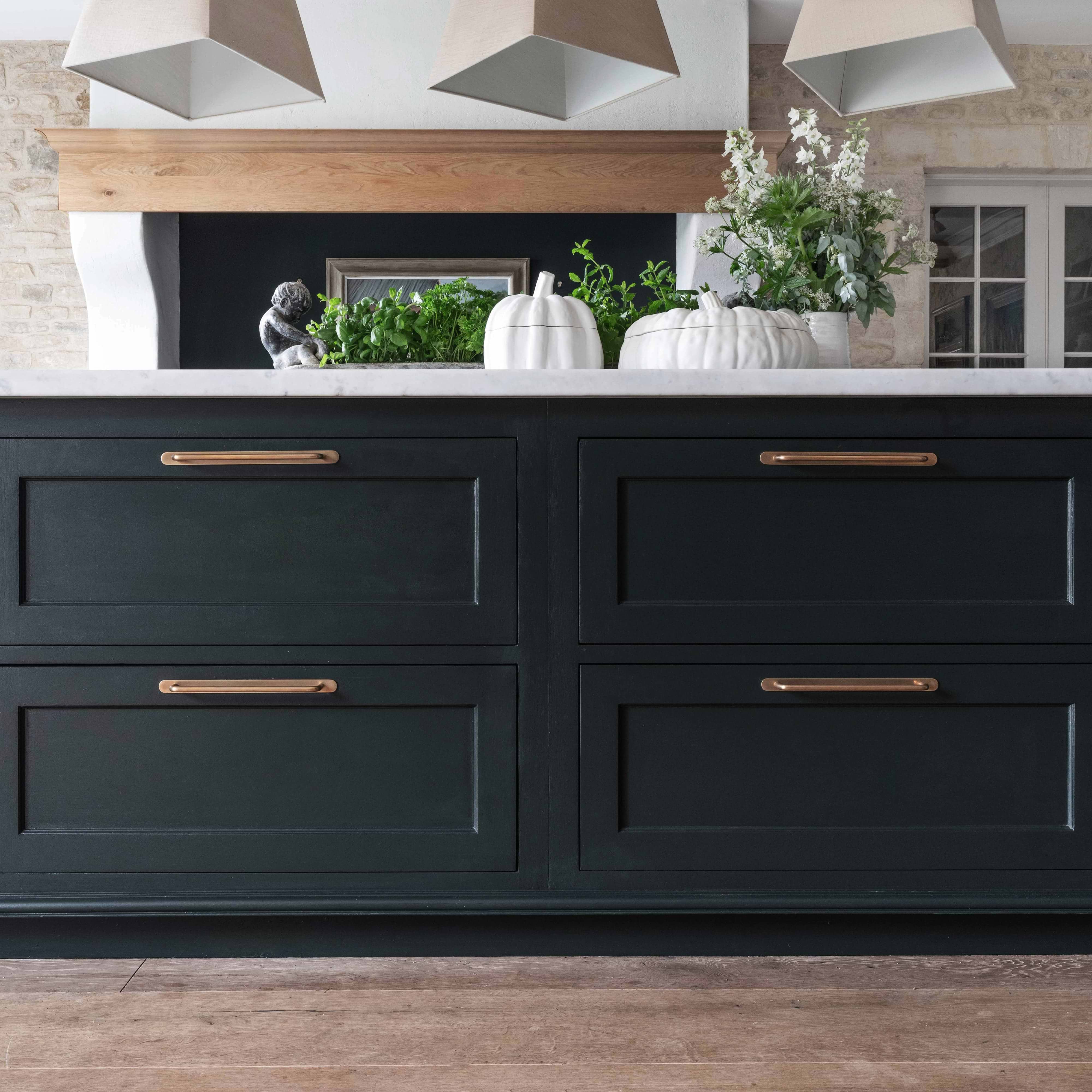 Close-up of Kilburn Furniture Handle Large in Antique Brass mounted on a dark green cabinet drawer.