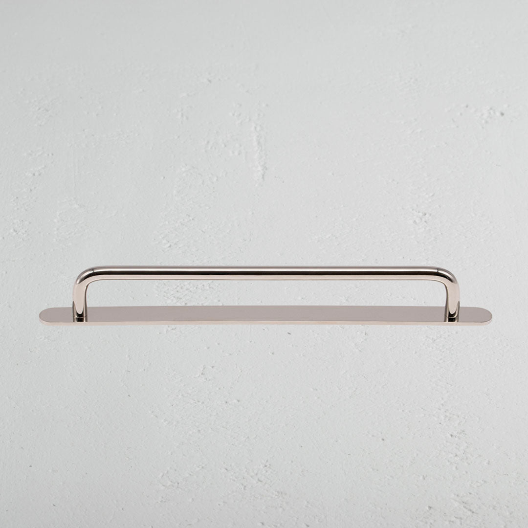 Kilburn Furniture Handle Medium in polished nickel, mounted horizontally on a white textured surface.