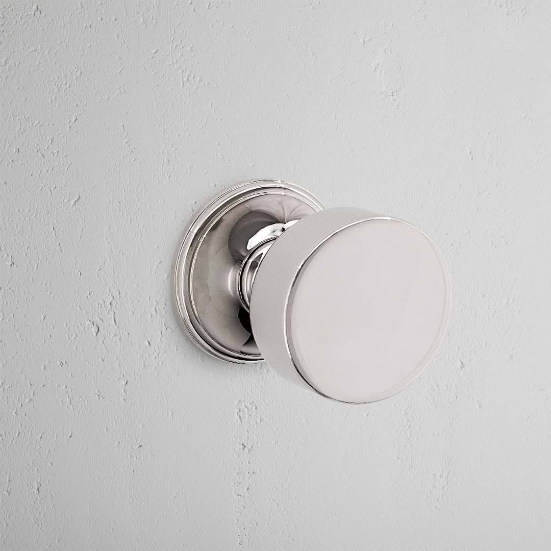 Onslow Dummy Door Knob Set in polished nickel finish, featuring a round, smooth design on a light wall.