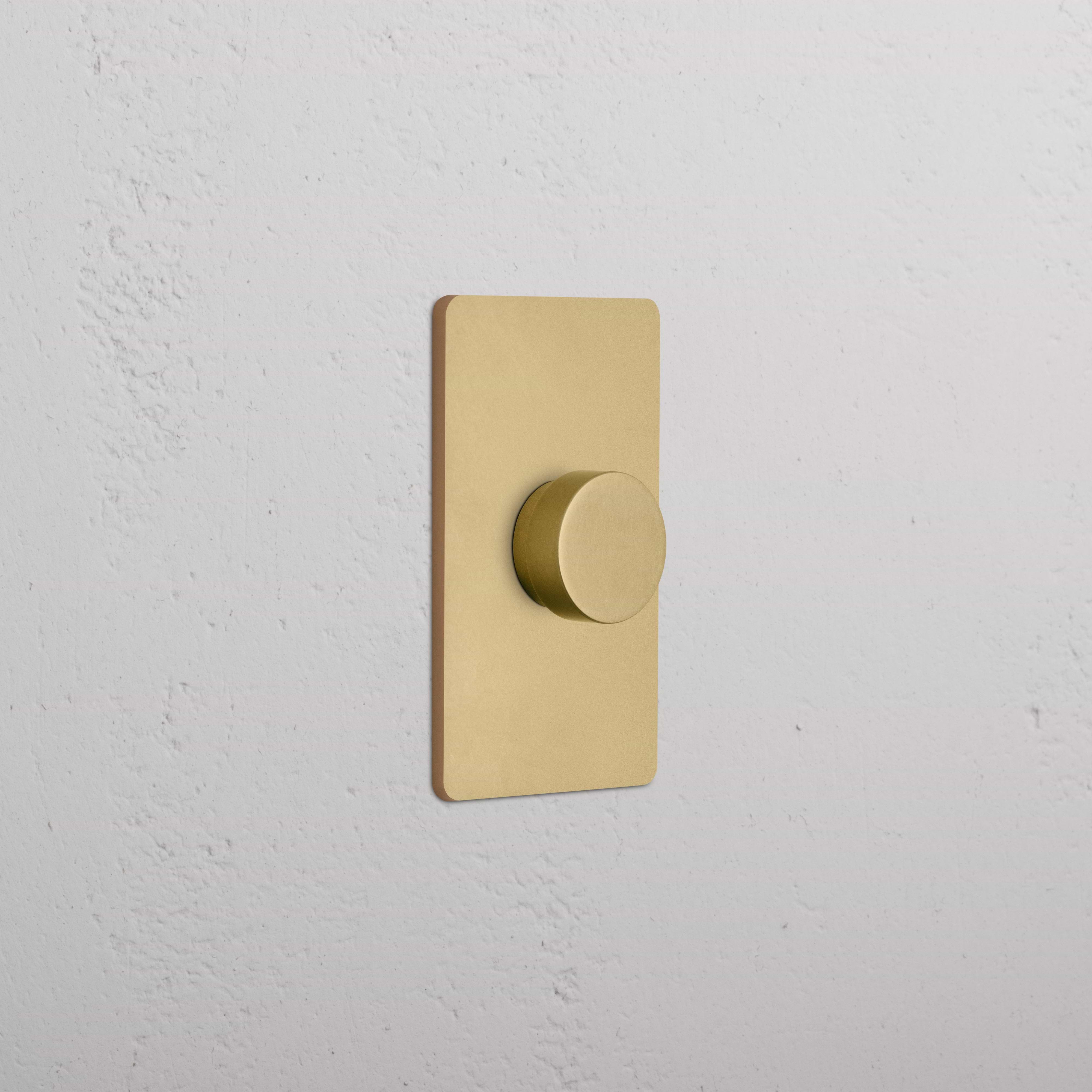 Grove 1G Dimmer Switch in Antique Brass with a round knob, shown mounted on a white wall.