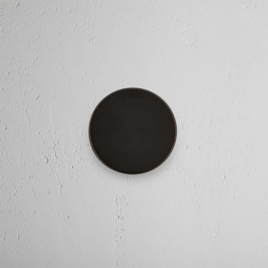 Bronze Onslow Passage Door Knob Set installed on a white textured wall, centered in the image.