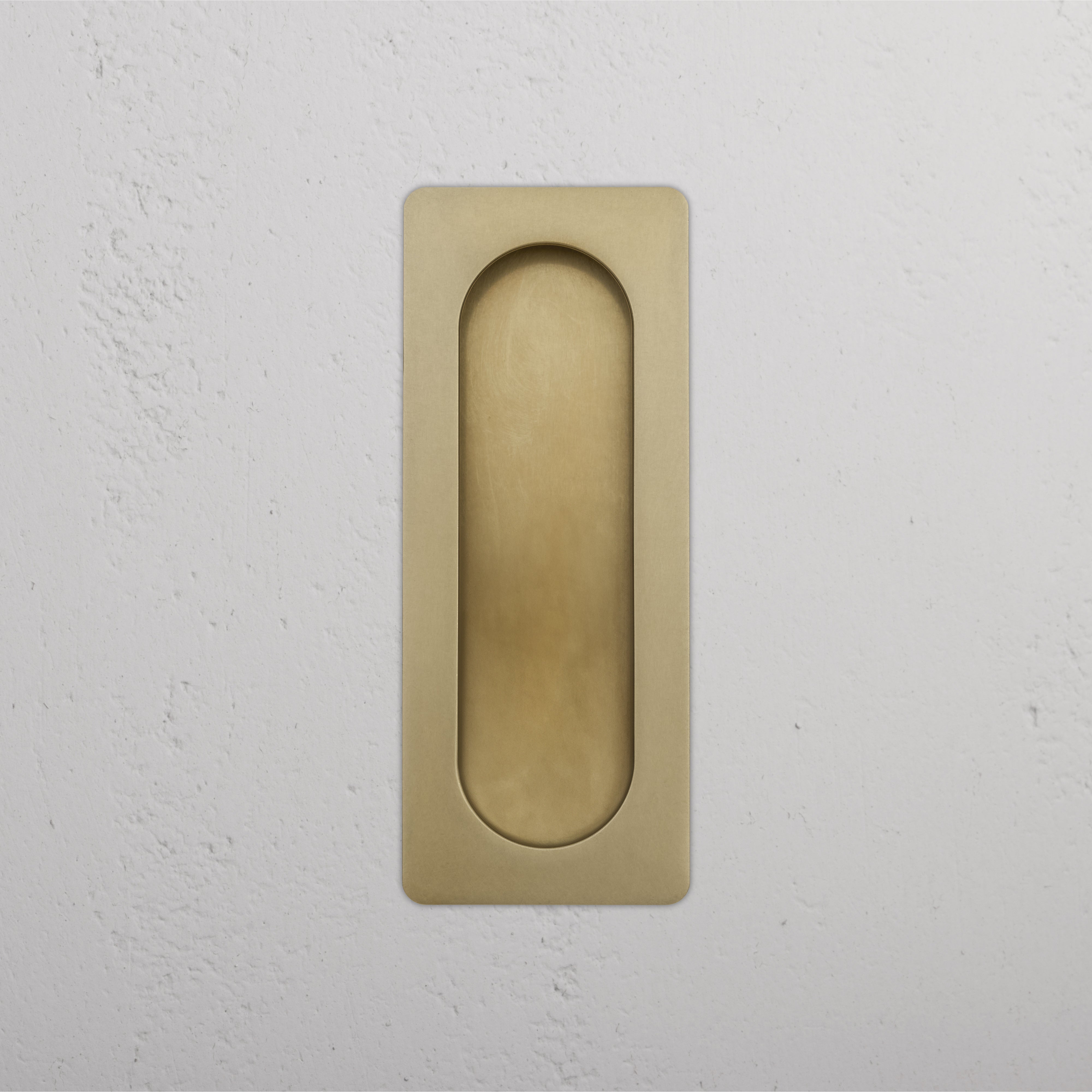Regent Recessed Medium Pull in antique brass with rounded edges, shown installed on a white wall.