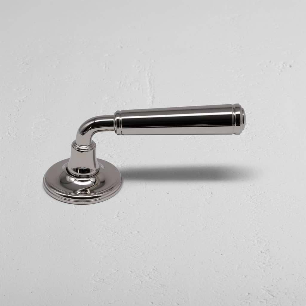 Polished nickel Digby Passage Door Handle Unsprung with rounded base and cylindrical grip on a light wall.