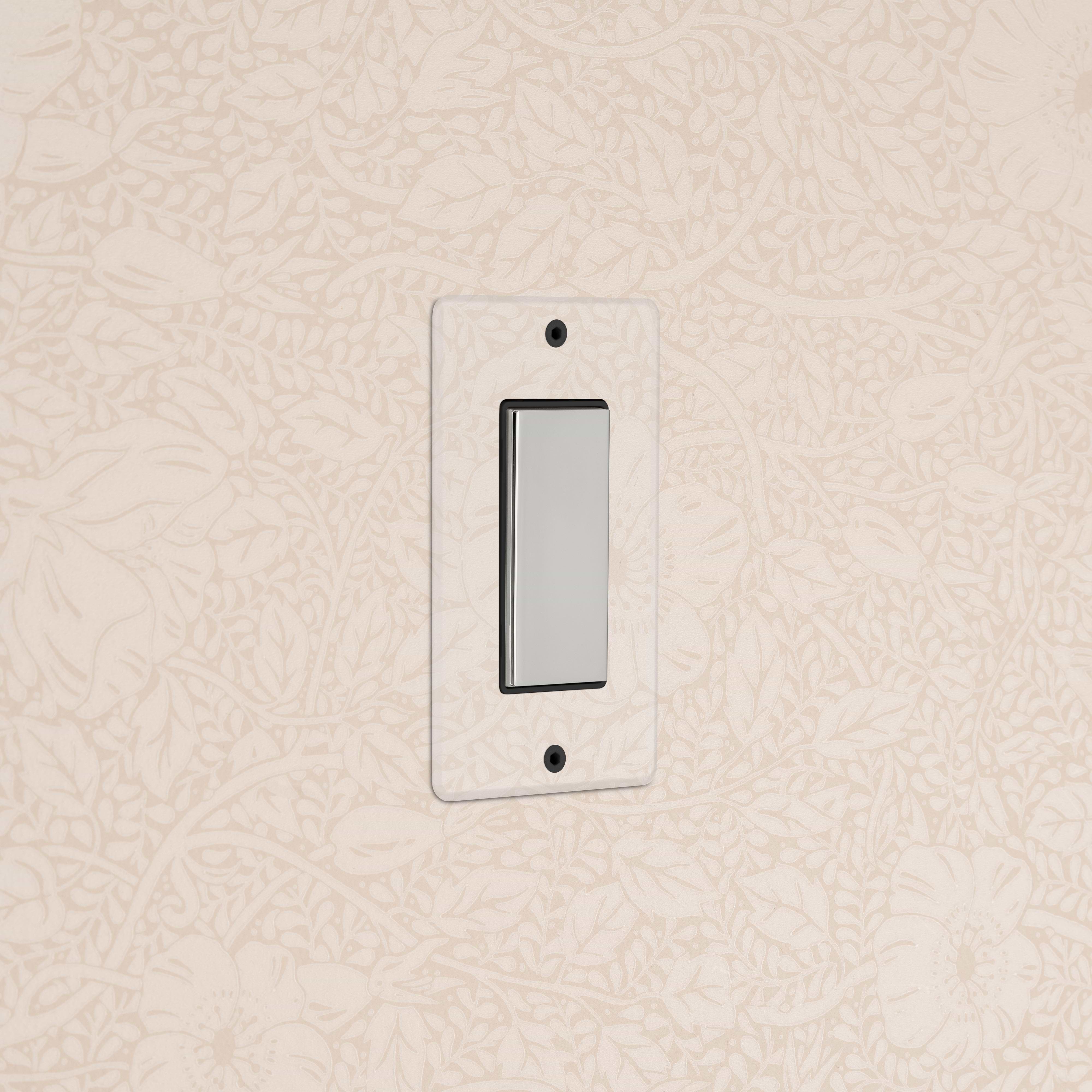 Kew 1G Center Retractive Rocker Switch in clear polished nickel black, mounted on floral wallpapered wall.