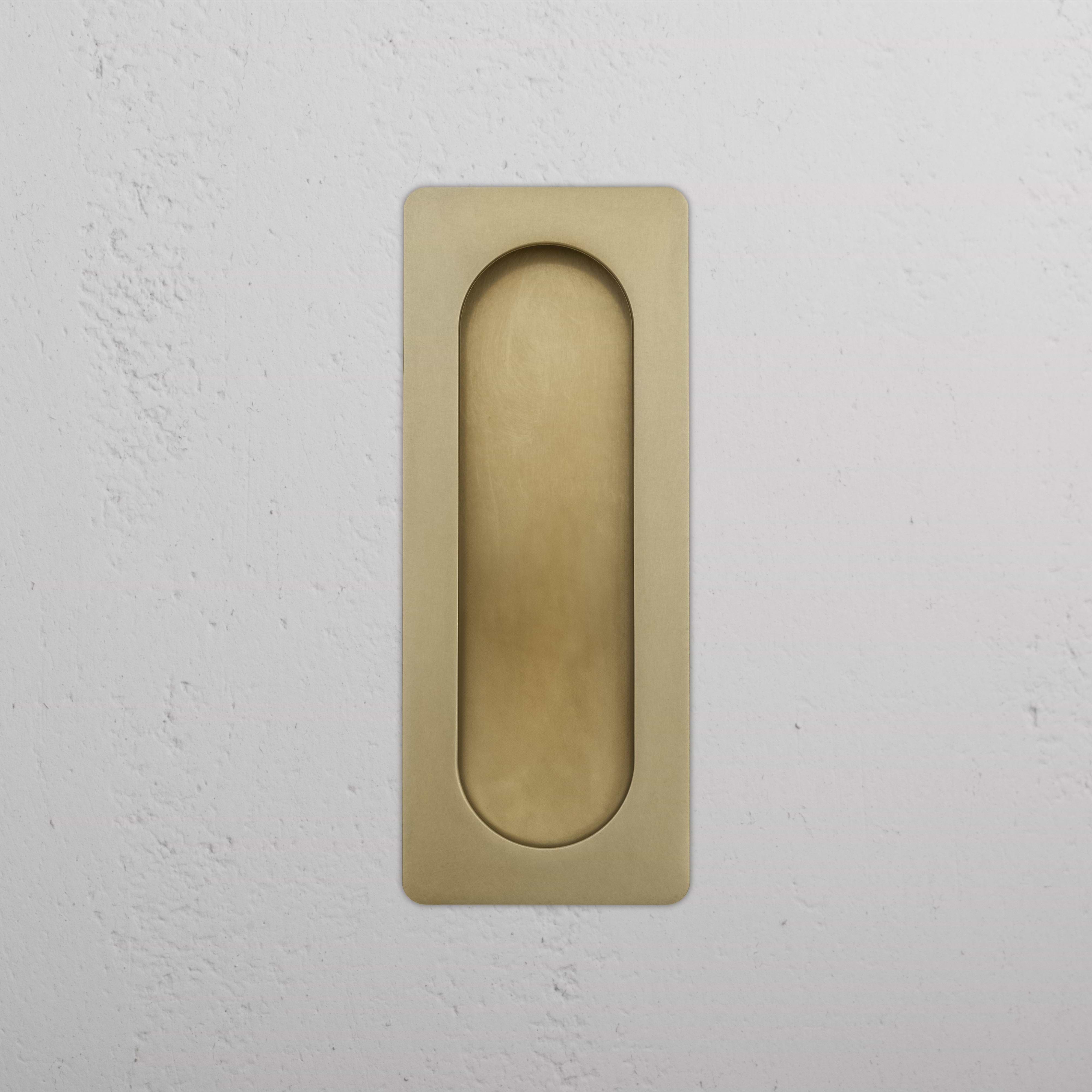 Regent Recessed Medium Pull in antique brass with rounded edges, shown installed on a white wall.