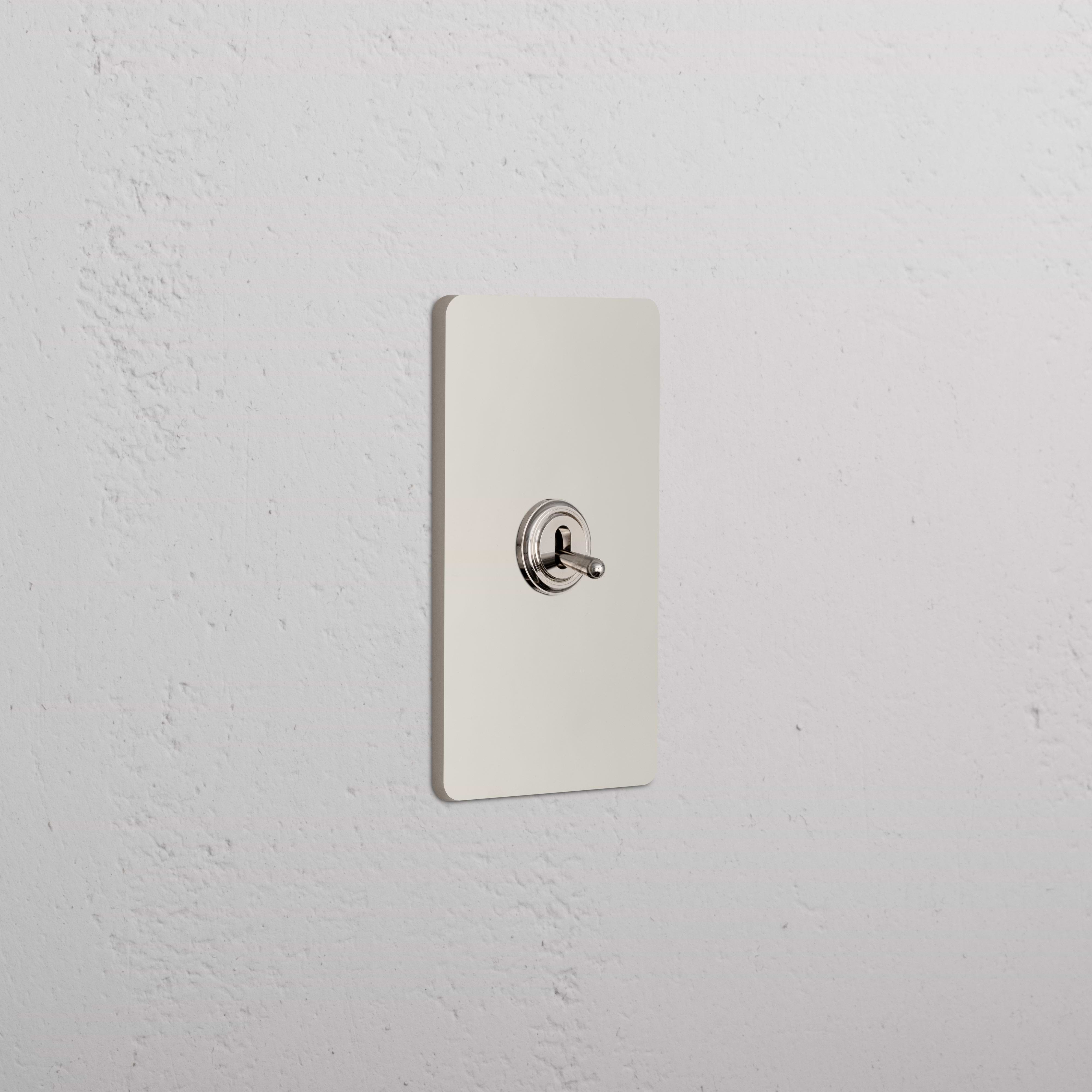 Grove 1G Toggle Switch in polished nickel, rectangular plate with rounded edges on a white textured wall.