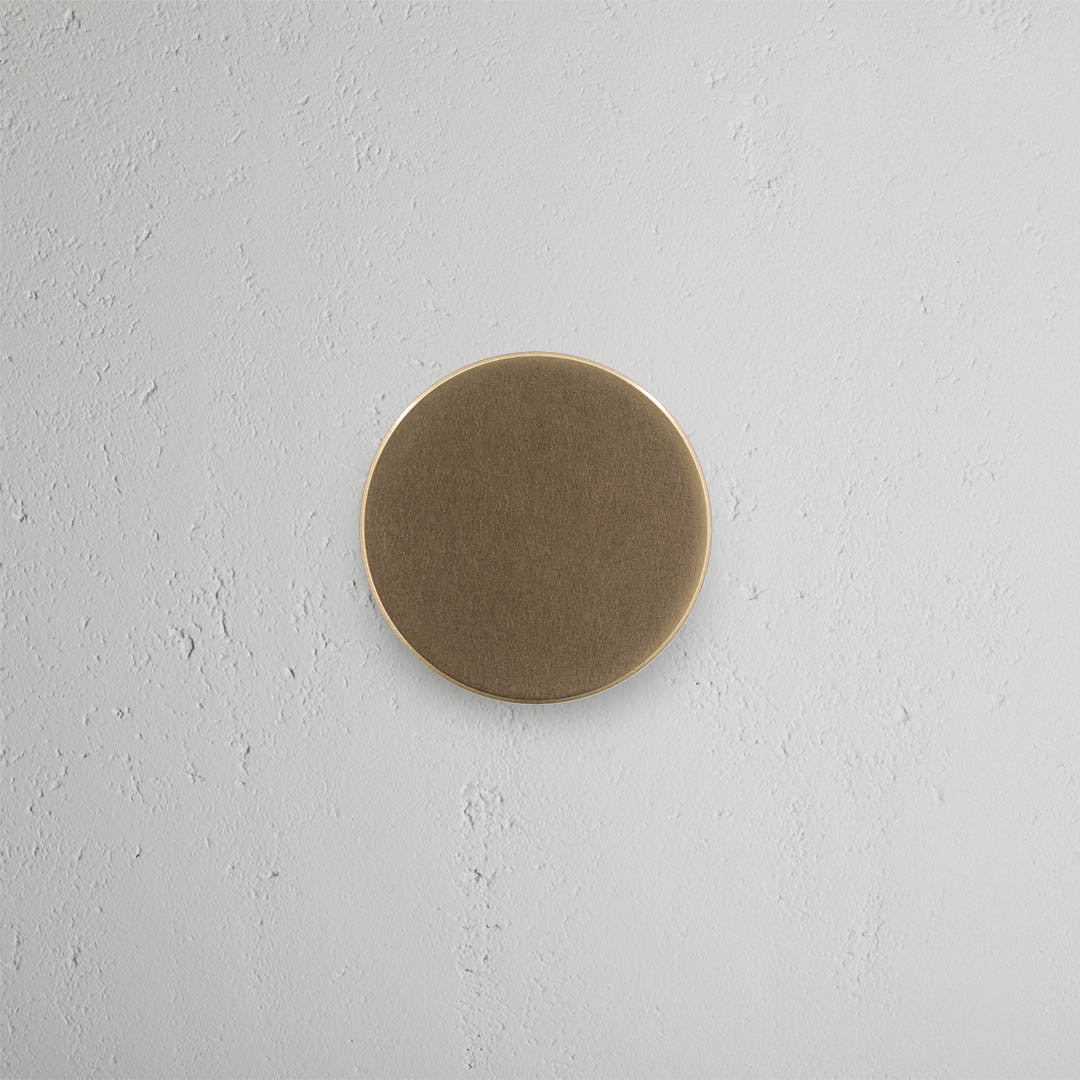 Onslow Passage Door Knob Set in antique brass with a round, matte finish mounted on a light gray door.