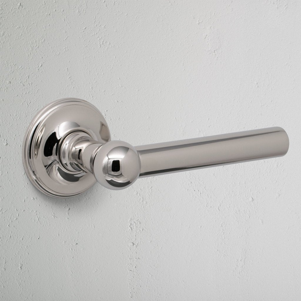 Harper Dummy Door Handle Set in polished nickel with round base, shown mounted on a white wall.