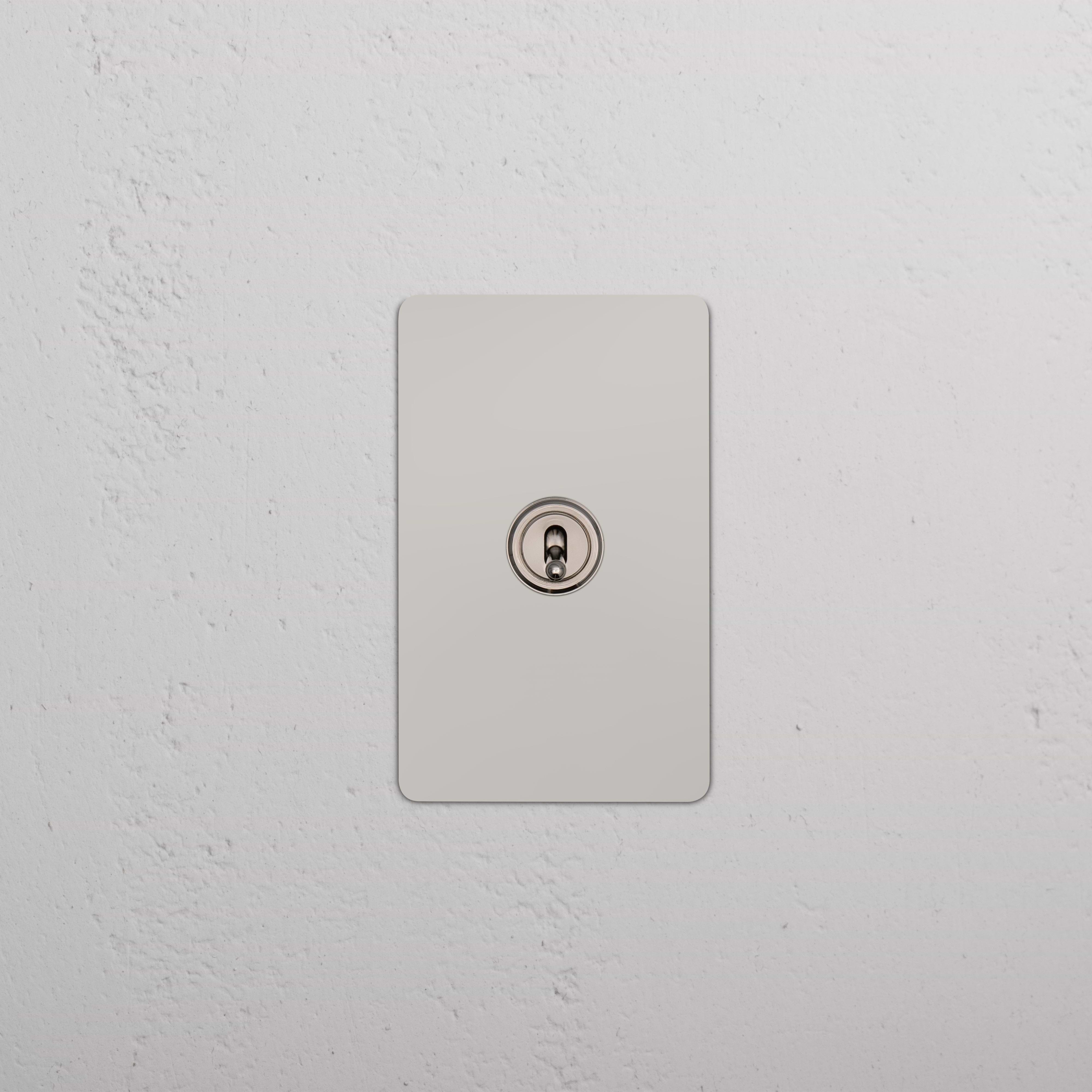 Kew 1G Toggle Switch in polished nickel finish, mounted on a white textured wall.