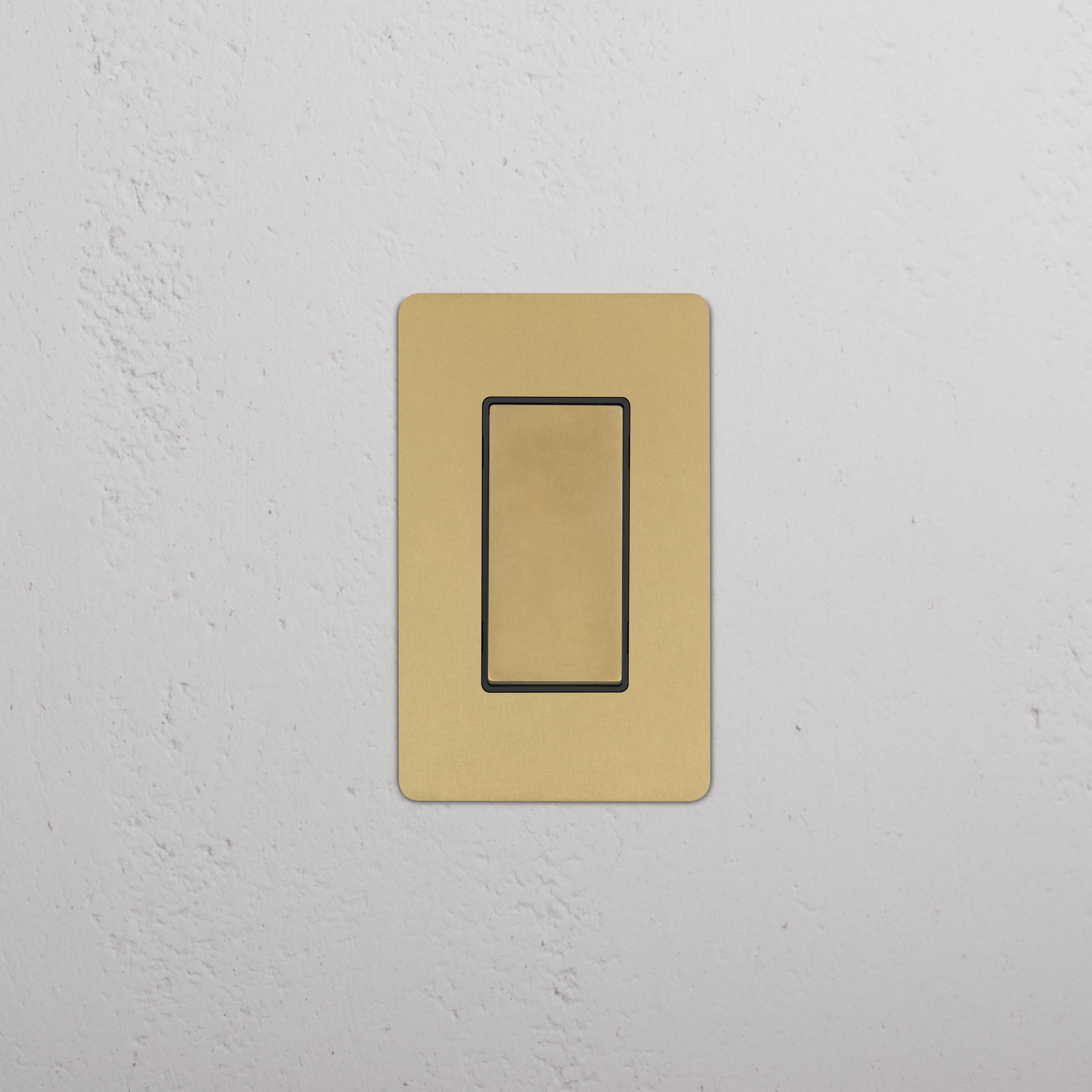 Kew 1G Retractive Rocker Switch in Antique Brass Black finish, mounted on a white textured wall.