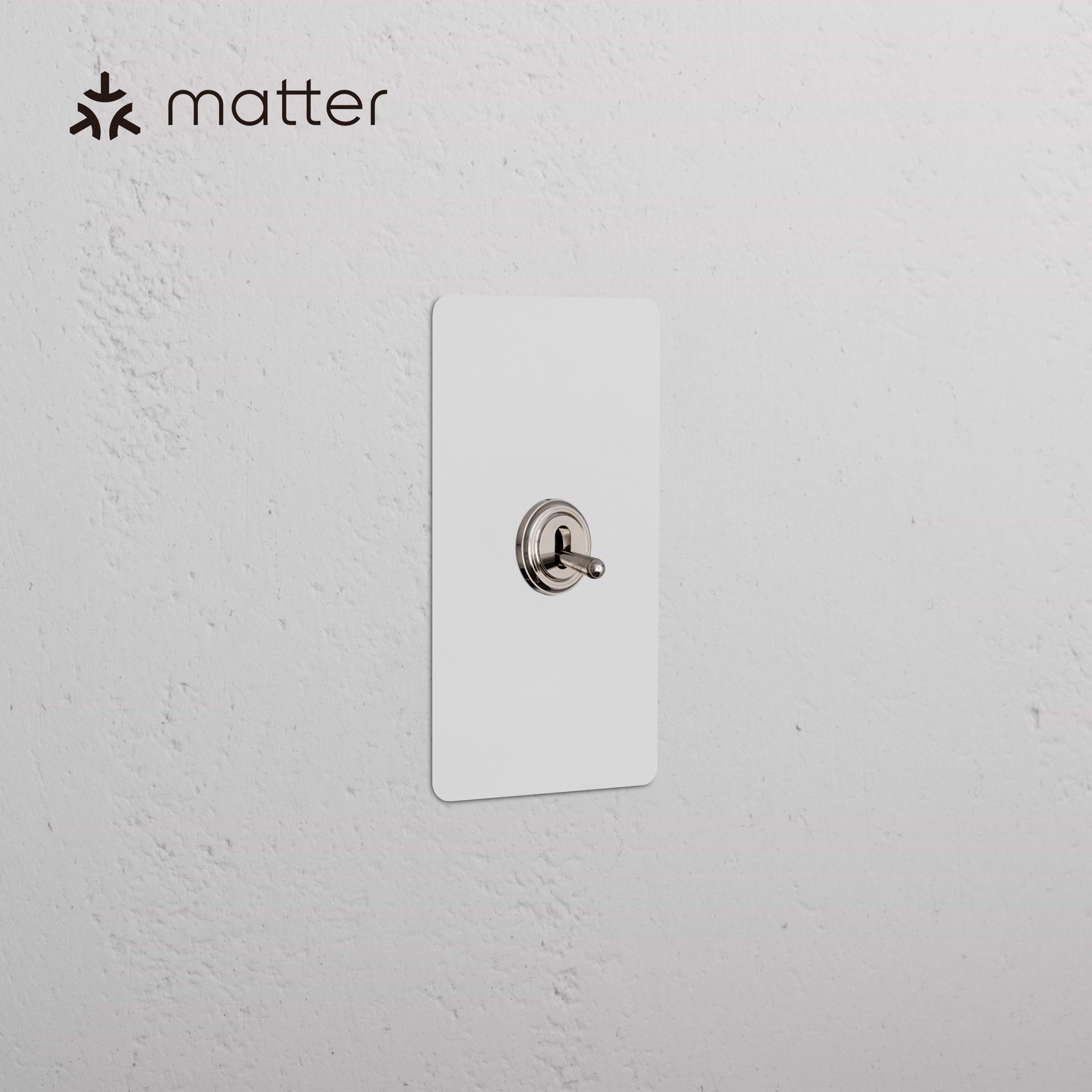 Kew 1G Smart Retractive Toggle Switch in paintable polished nickel, shown mounted on a white wall.
