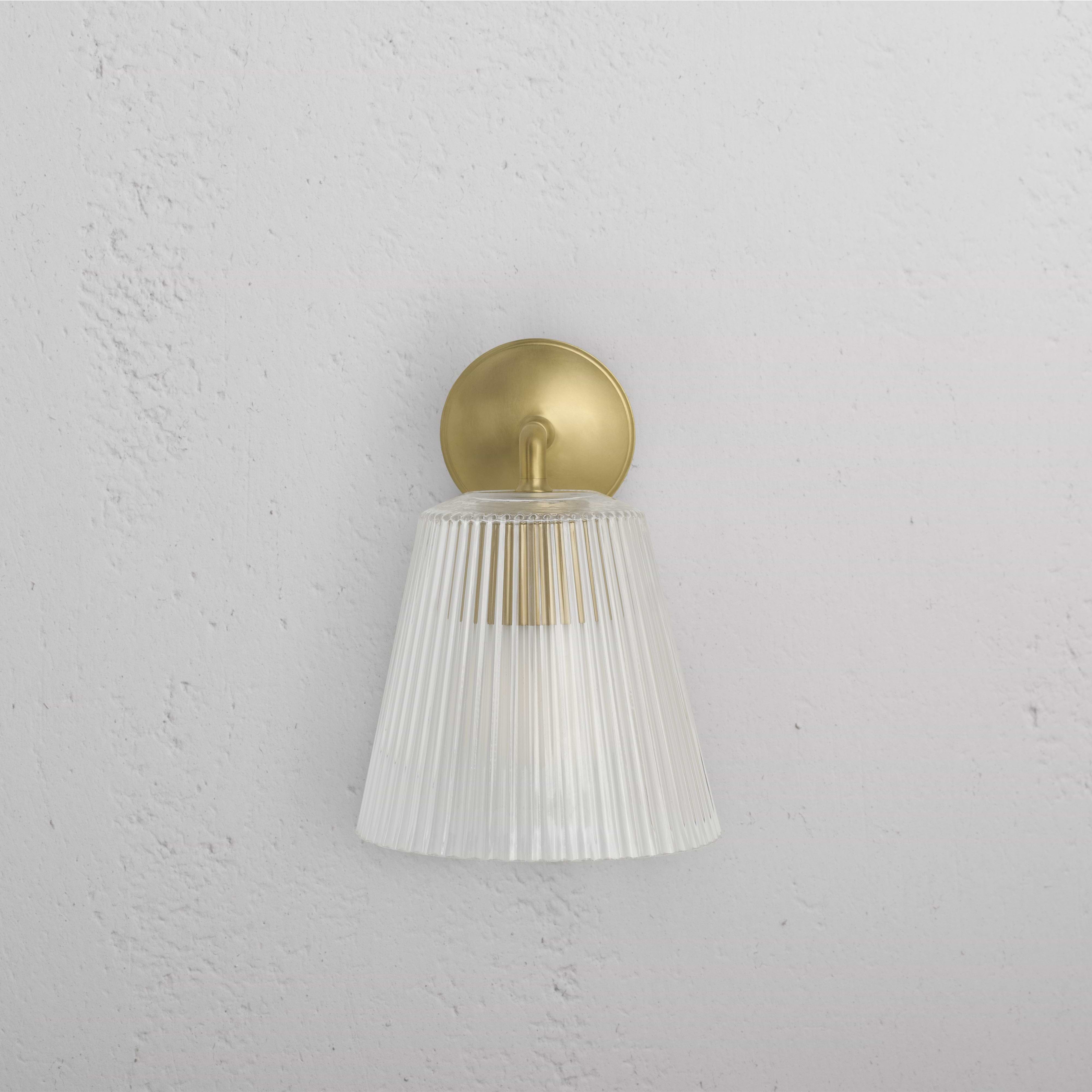 Large Richmond Wall Light in antique brass with fluted glass shade, mounted on a white textured wall.