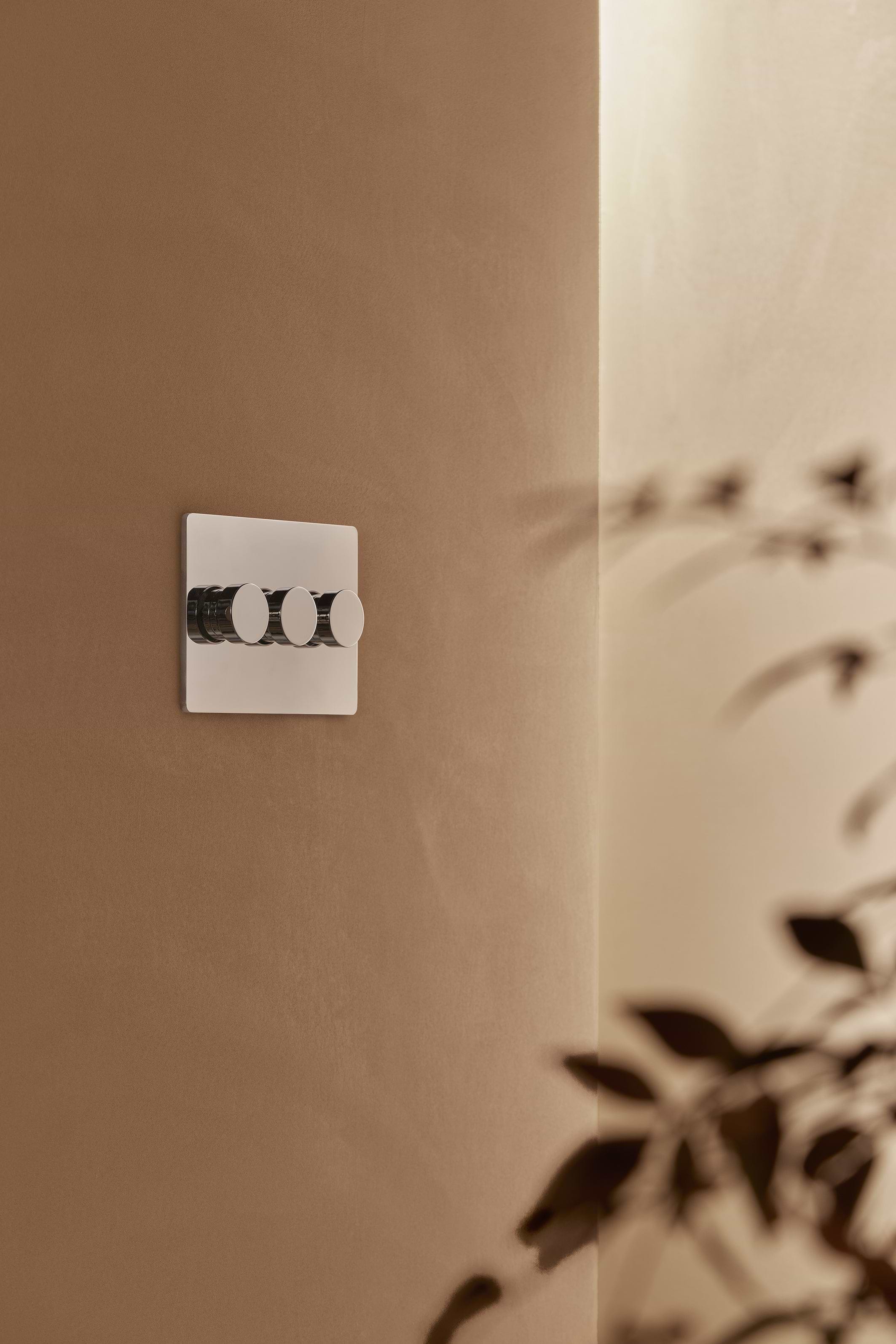 Grove 3G Dimmer Switch in polished nickel with three round dials, mounted on a beige wall.