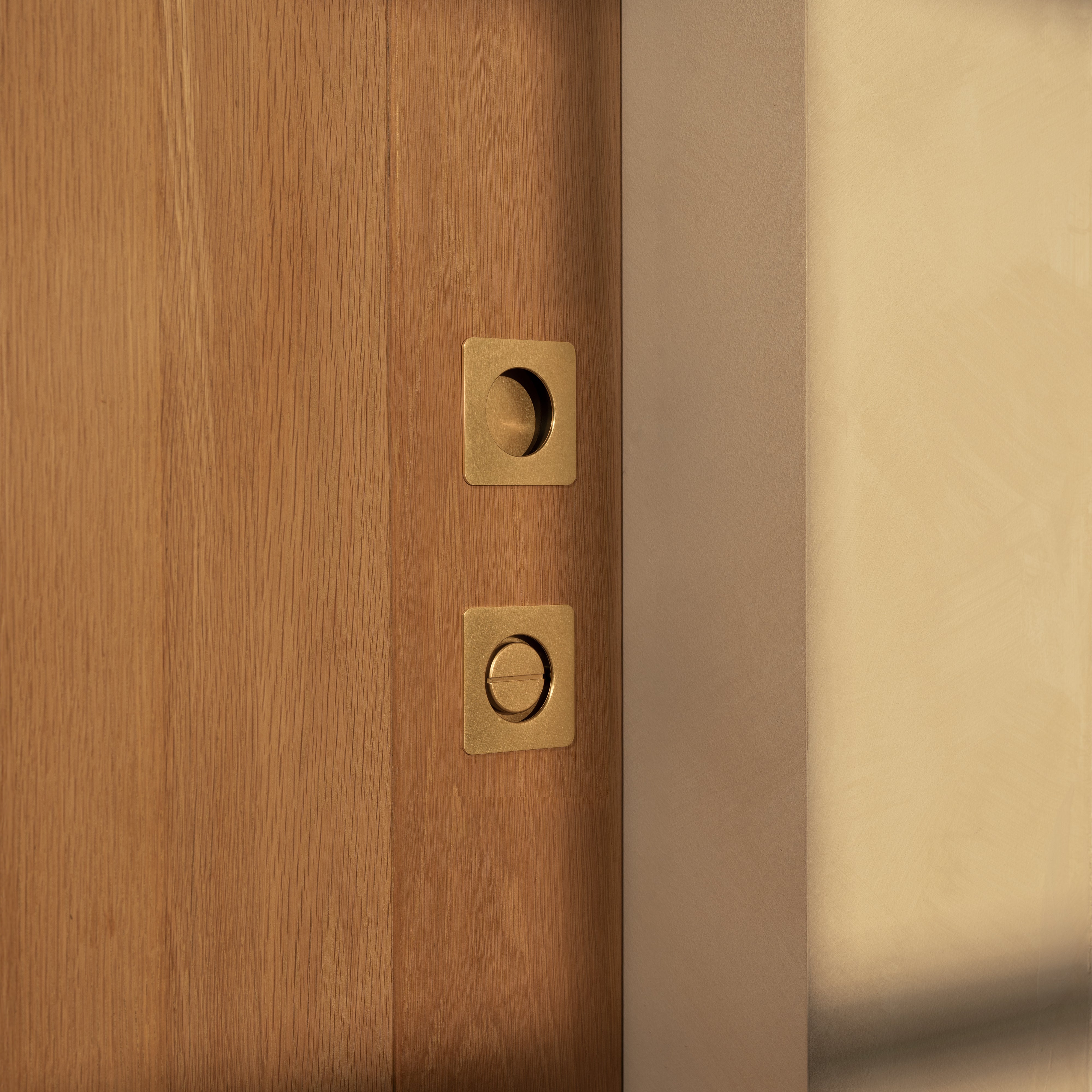Regent Recessed Thumbturn in antique brass, installed on a wooden door, showing square thumbturn design.