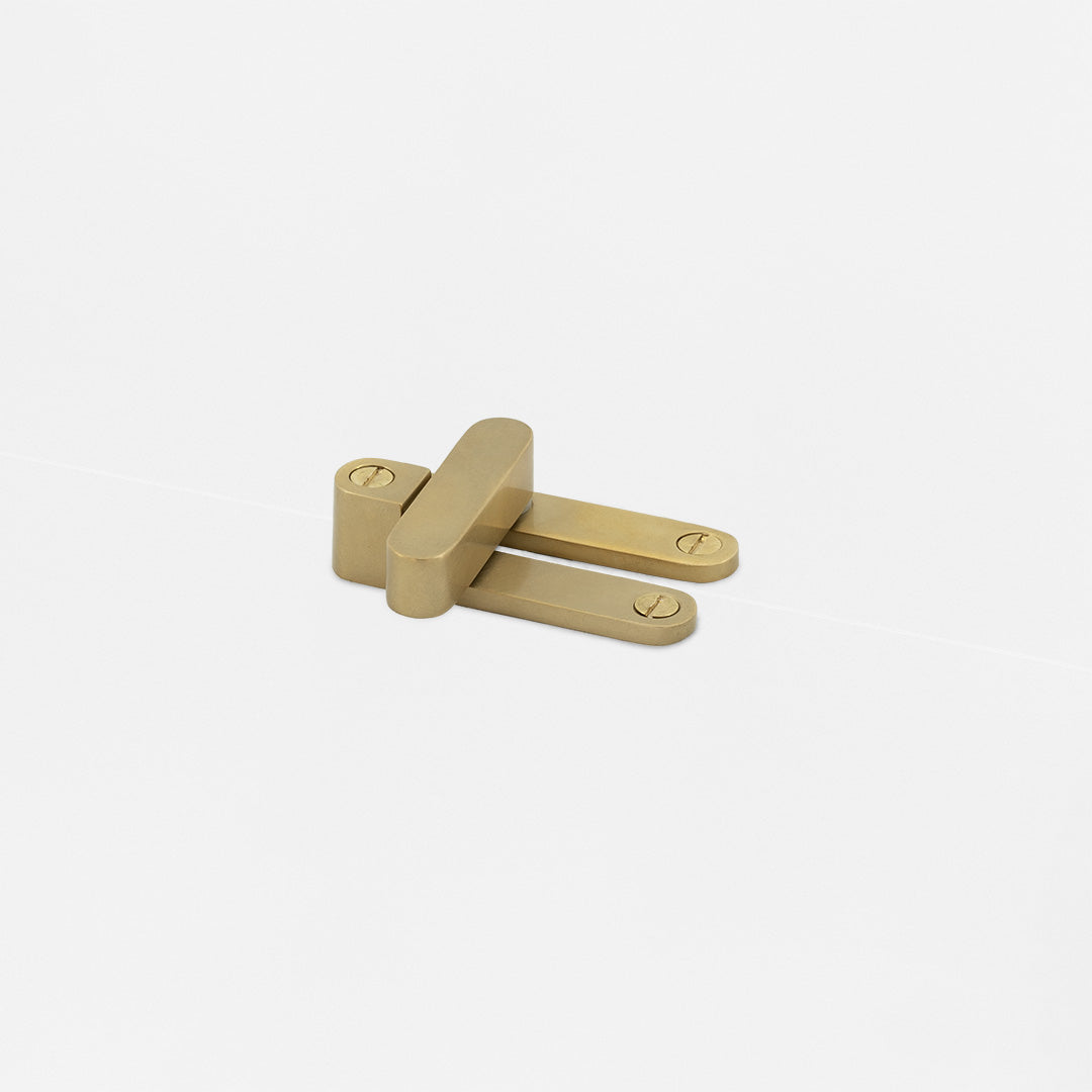 Belmont Single Hung Window Latch in antique brass with two flat arms, installed on a white surface.